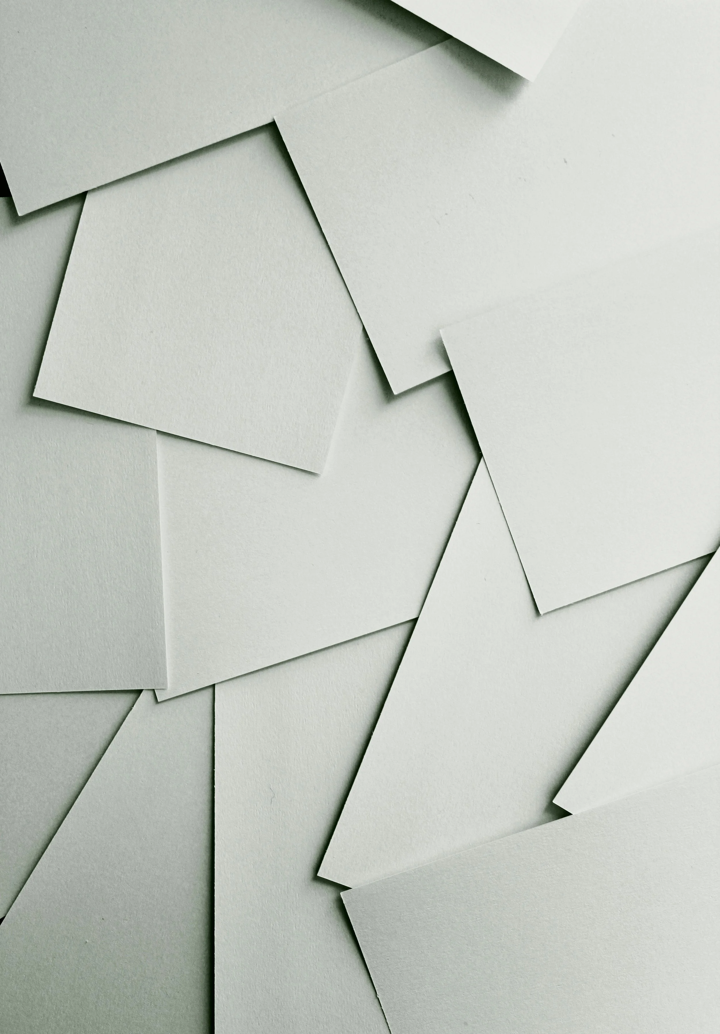 Multiple overlapping blank white paper sheets arranged on a flat surface.
