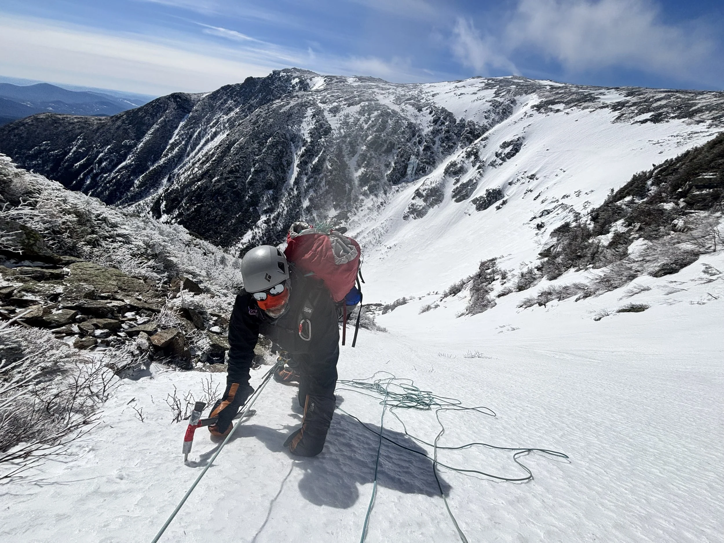 Climber ascending step slop with ice ax and crampons