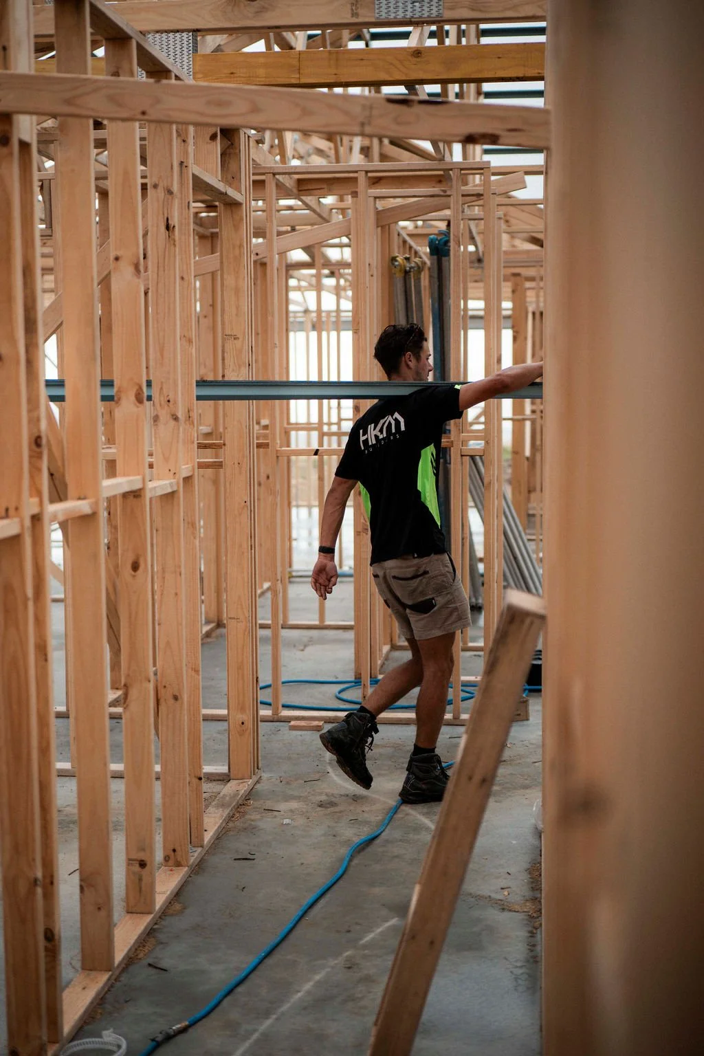 A construction worker building wooden framing inside a house under construction.