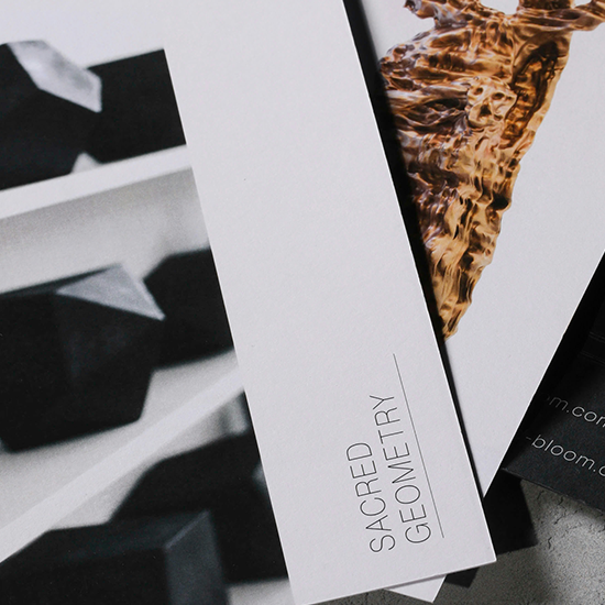 Close-up of printed materials with abstract images, including one showing water with ripples and another showing black geometric shapes, and text that reads 'Sacred Geometry'.