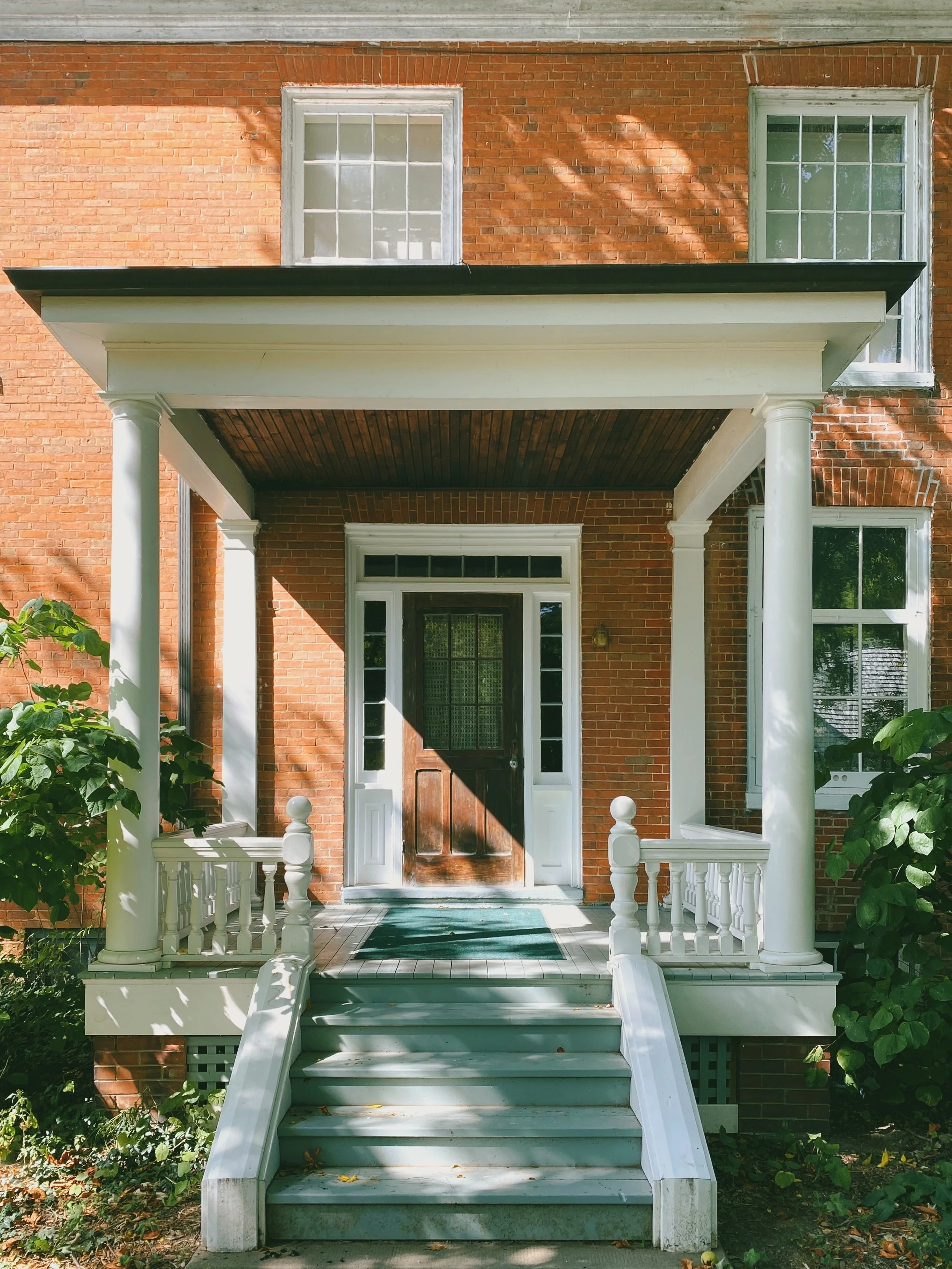 Front porch repair and renovation with tapered columns, new railings, hardwood deck, and painted finish.  Saratoga Springs, NY.