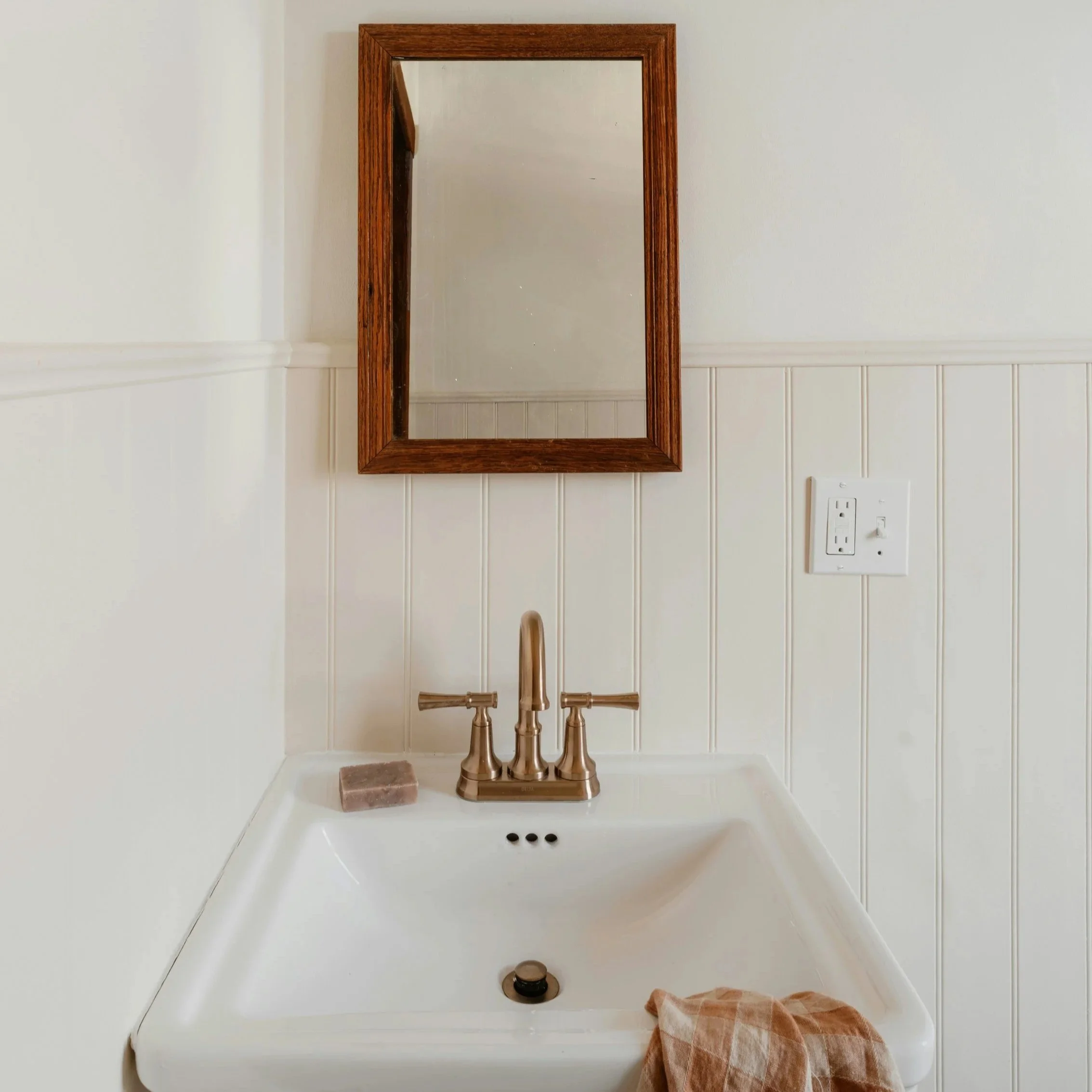 Powder room renovation featuring pedastal sink, brass faucet, beadboard wall paneling,  and fresh paint in Saratoga Springs, NY.