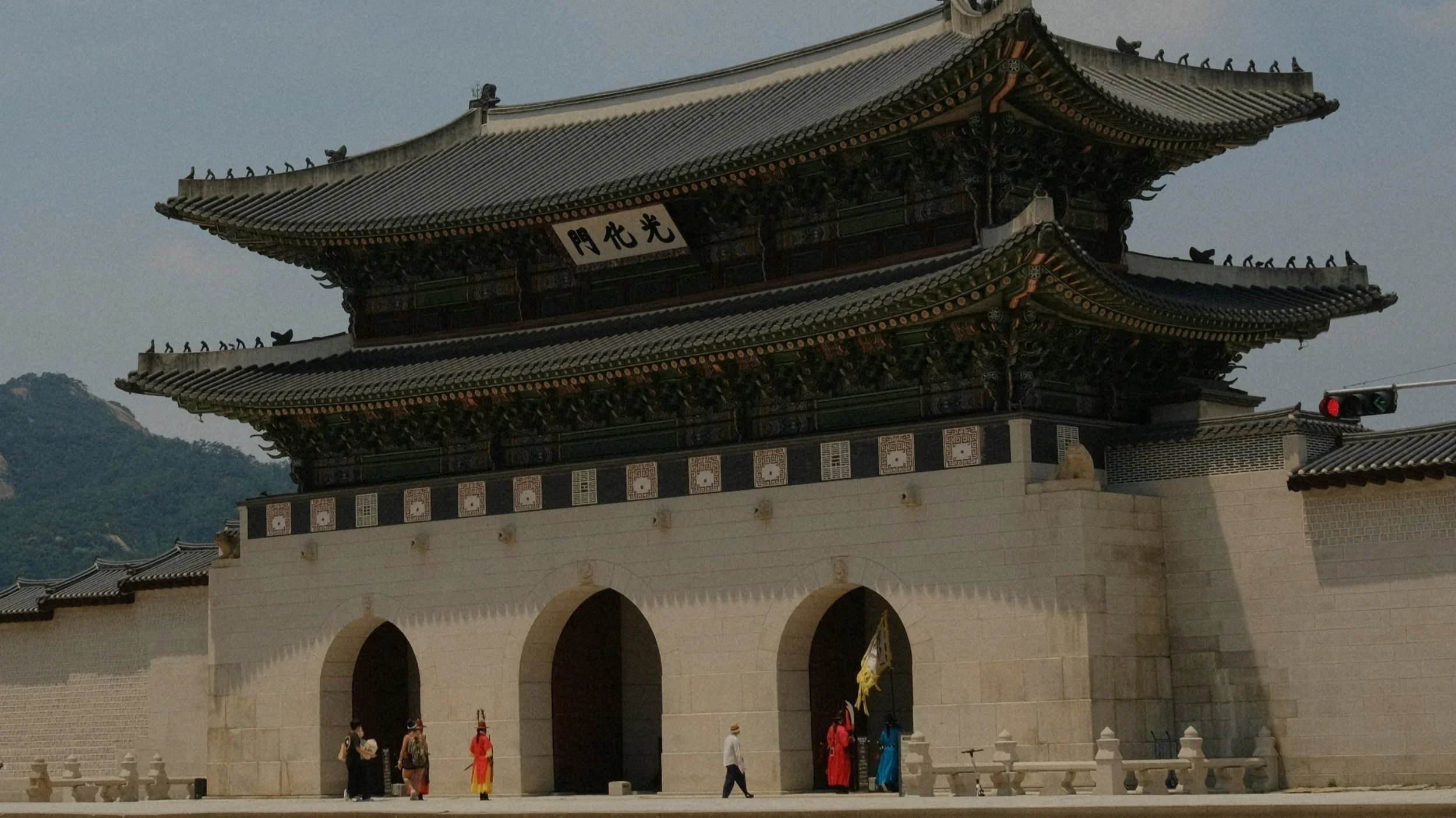 Imposing two tiered Gwanghwamun Gate at Gyeongbokgung Palace in Seoul with royal guards in traditional dress standing beneath the arched stone entryway