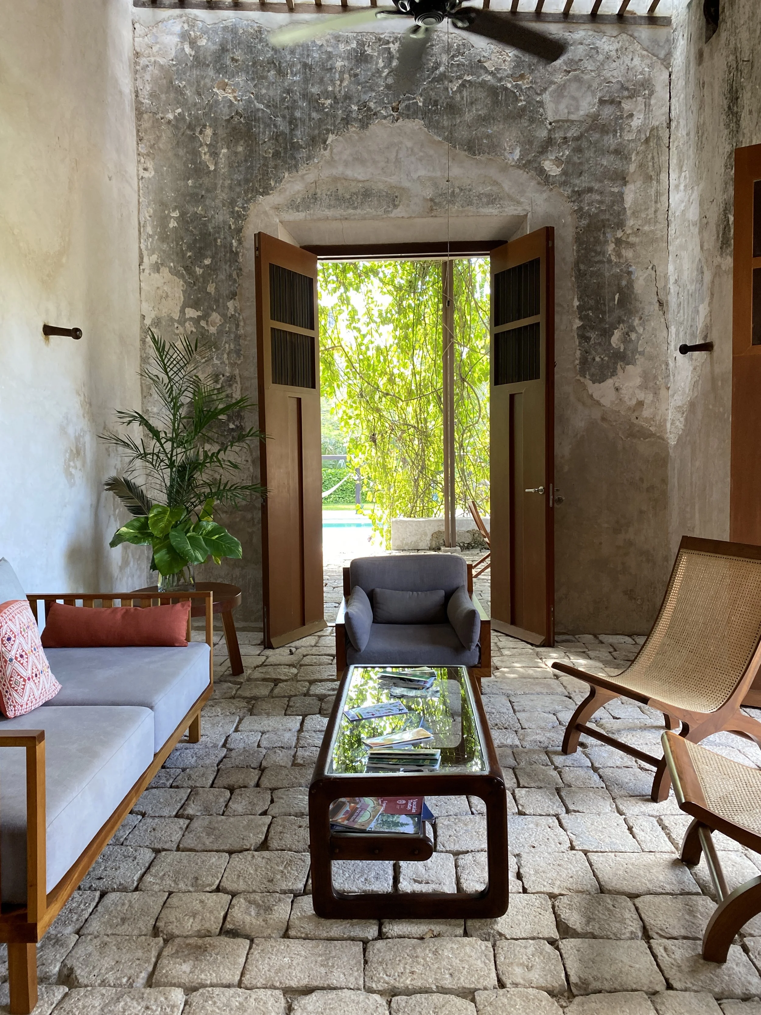 Elegant interior of a restored colonial hacienda with open wooden doors and a garden view in the Yucatán, Mexico