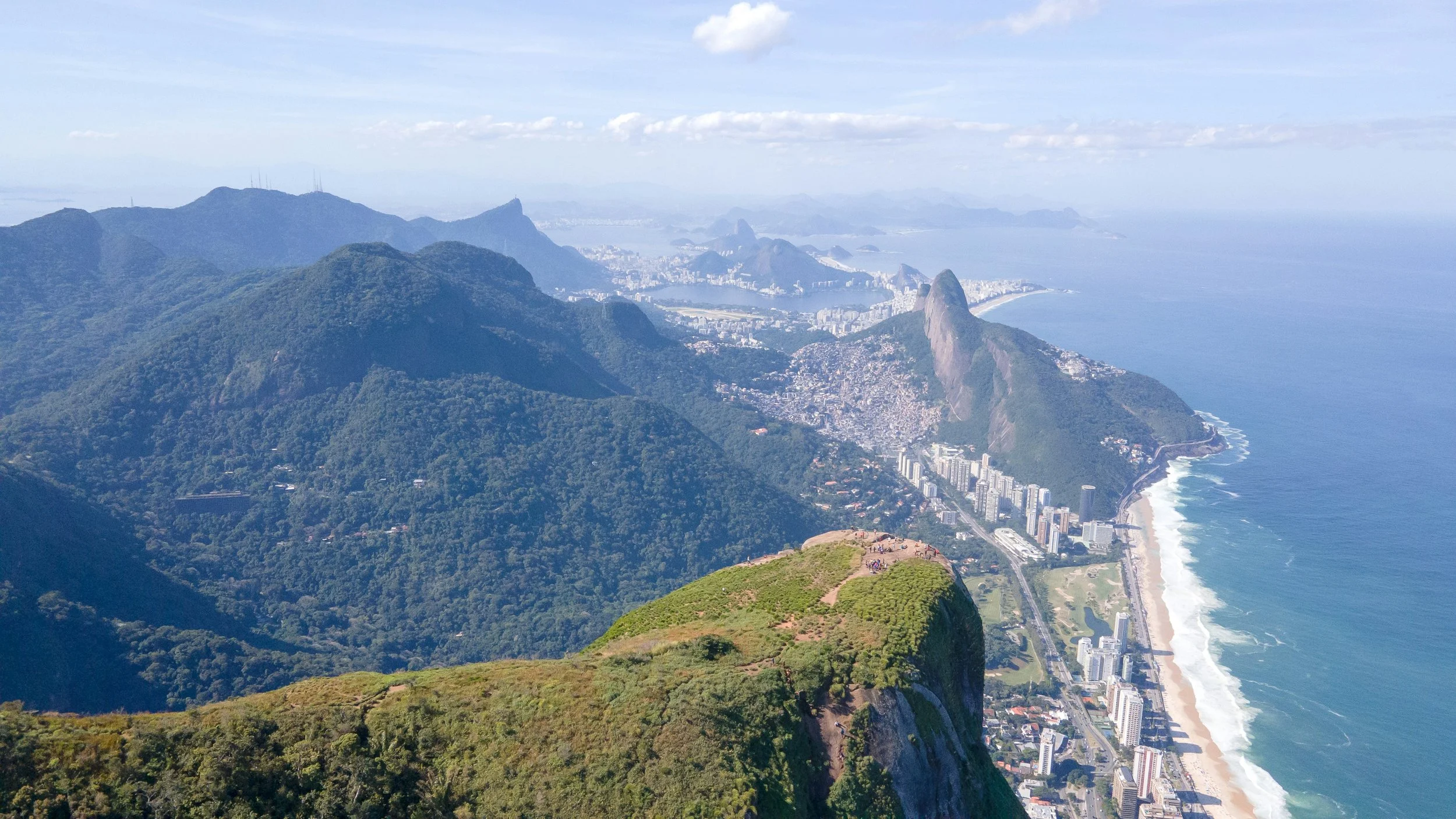 Sweeping aerial view over Rio de Janeiro showing mountain peaks, coastline and the city stretching toward the Atlantic Ocean, Brazil