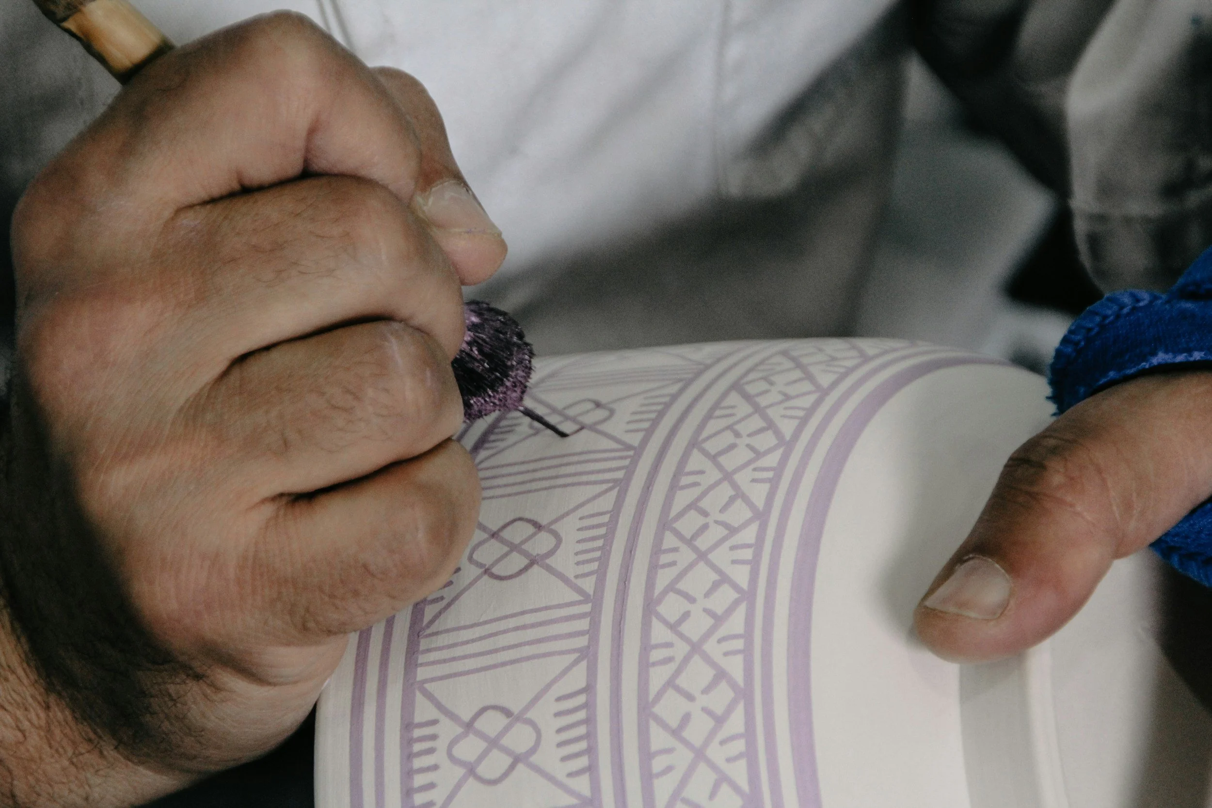 Moroccan artisan hand-engraving intricate geometric patterns on a ceramic piece in a medina workshop