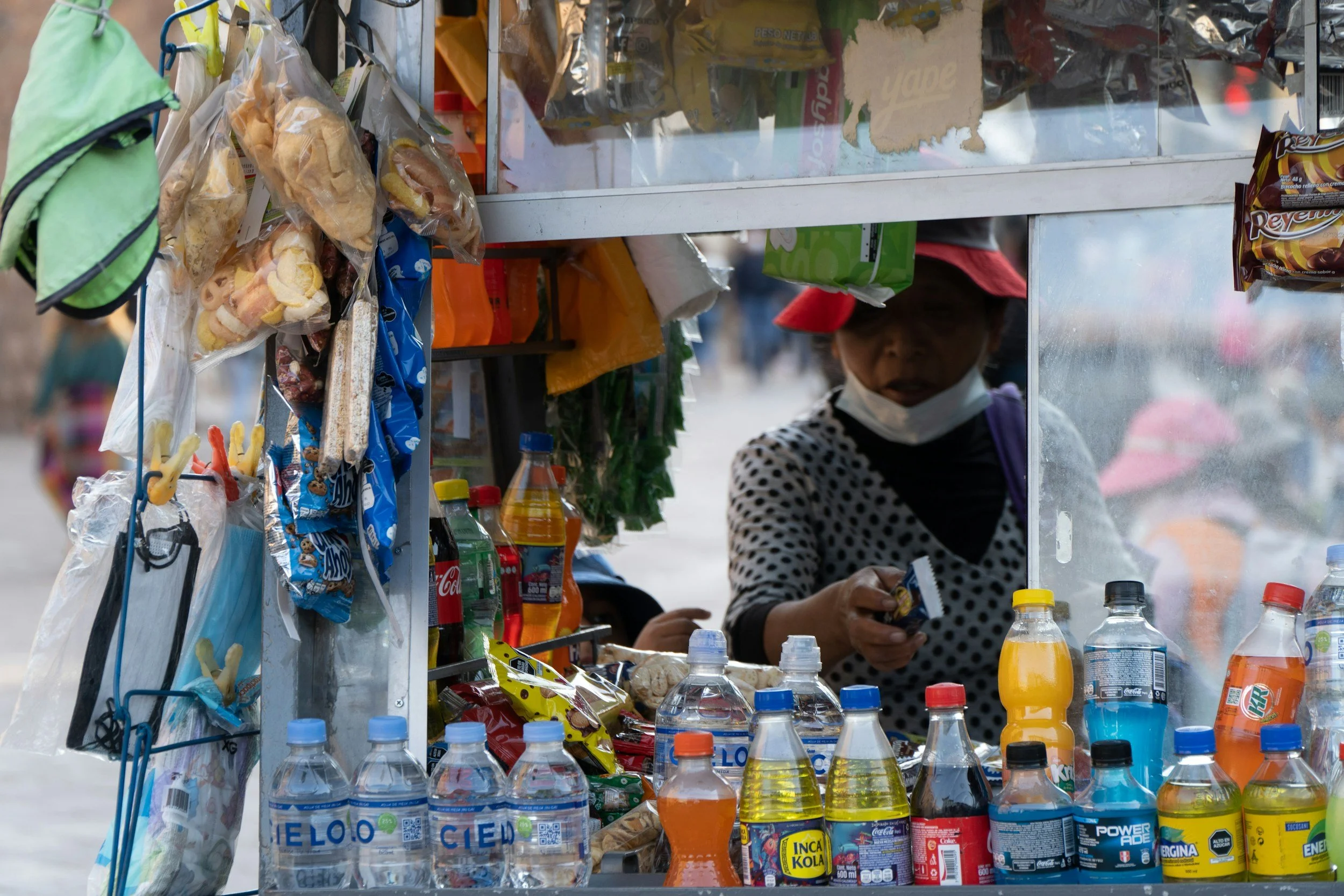 Local vendor at a street food stall in Cusco surrounded by snacks and drinks on a private food tour of Peru