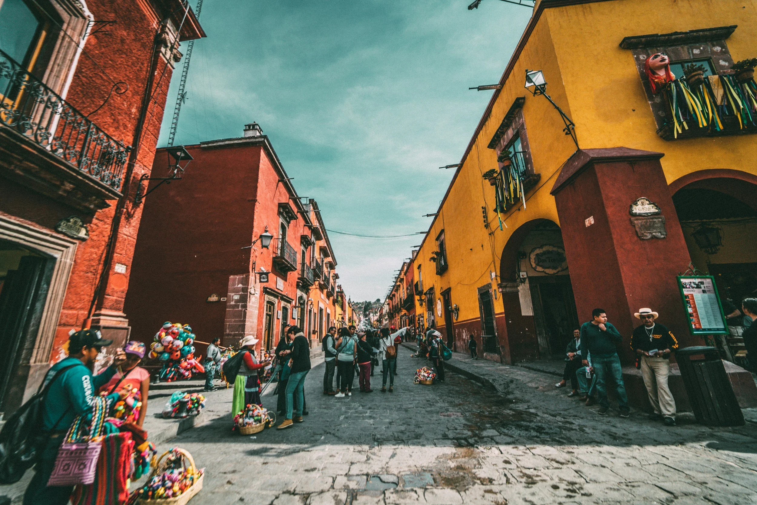 Colourful colonial facades and market vendors on a cobblestone street in the historic centre of San Miguel de Allende, Mexico