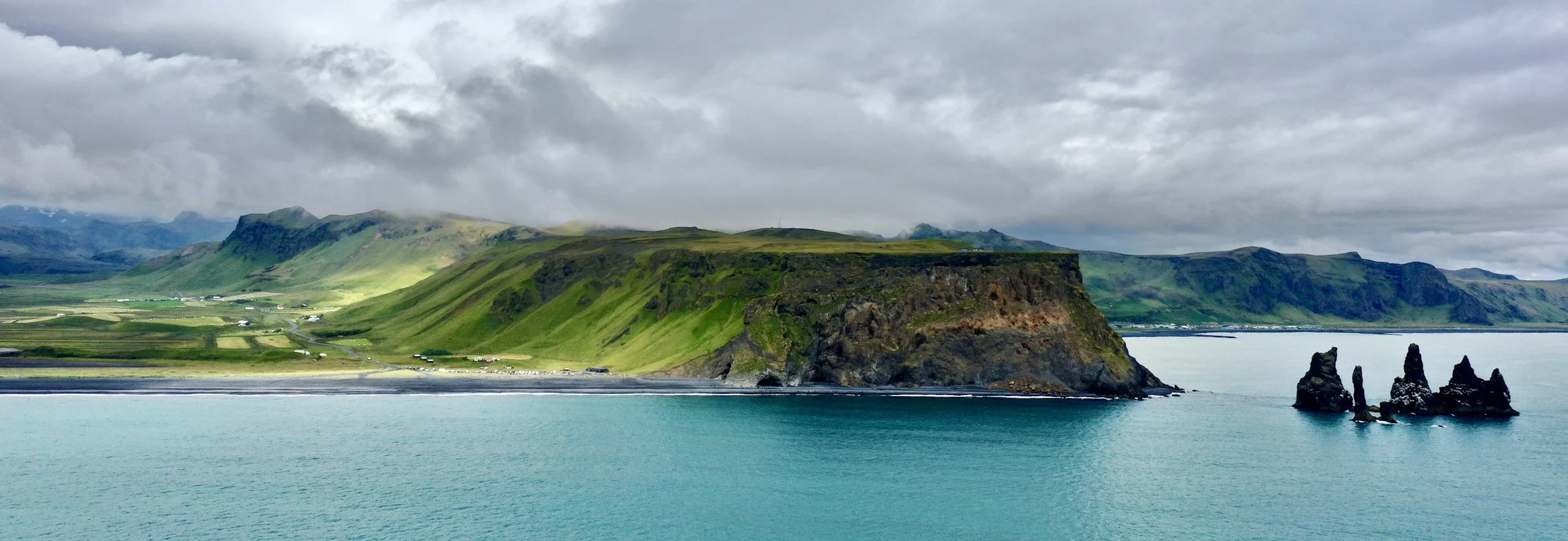 Dramatic green volcanic cliffs and turquoise water along the coastline of Jeju Island on a private tour of South Korea