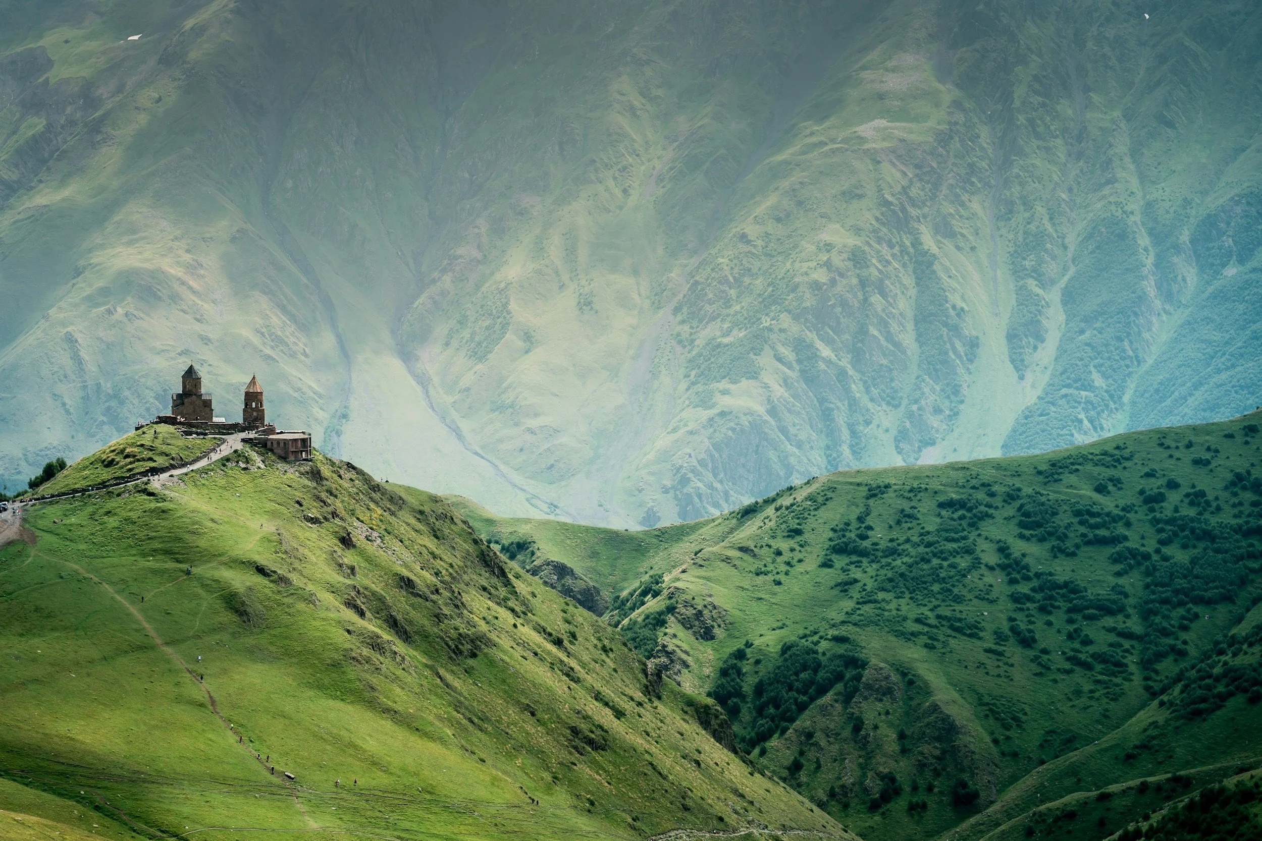 The medieval Gergeti Trinity Church perched on a dramatic ridge above deep Caucasus valleys near Kazbegi on a private tour of Georgia