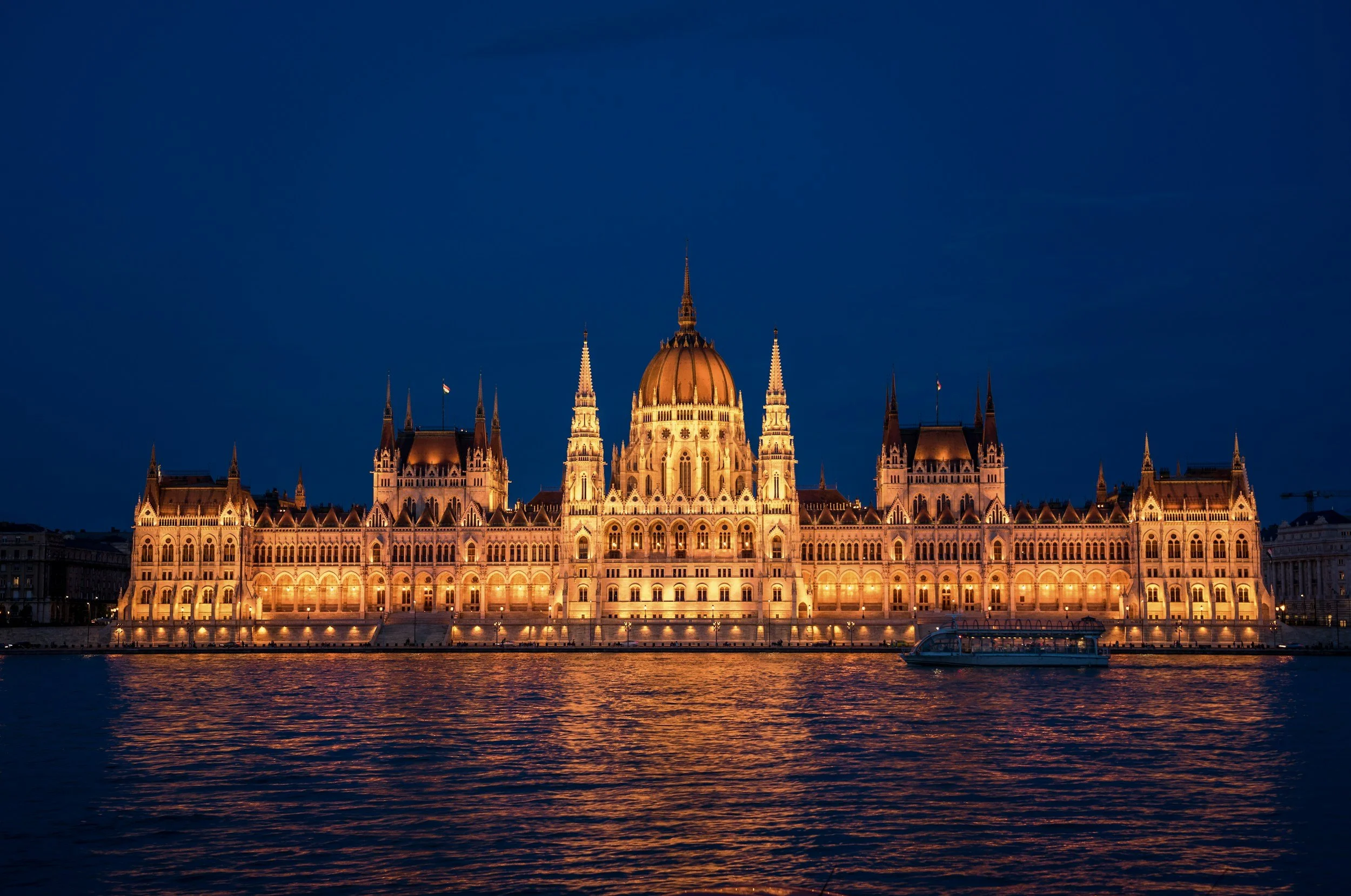 The neo-Gothic Hungarian Parliament Building lit up at night and reflected in the dark waters of the Danube River in Budapest, Hungary