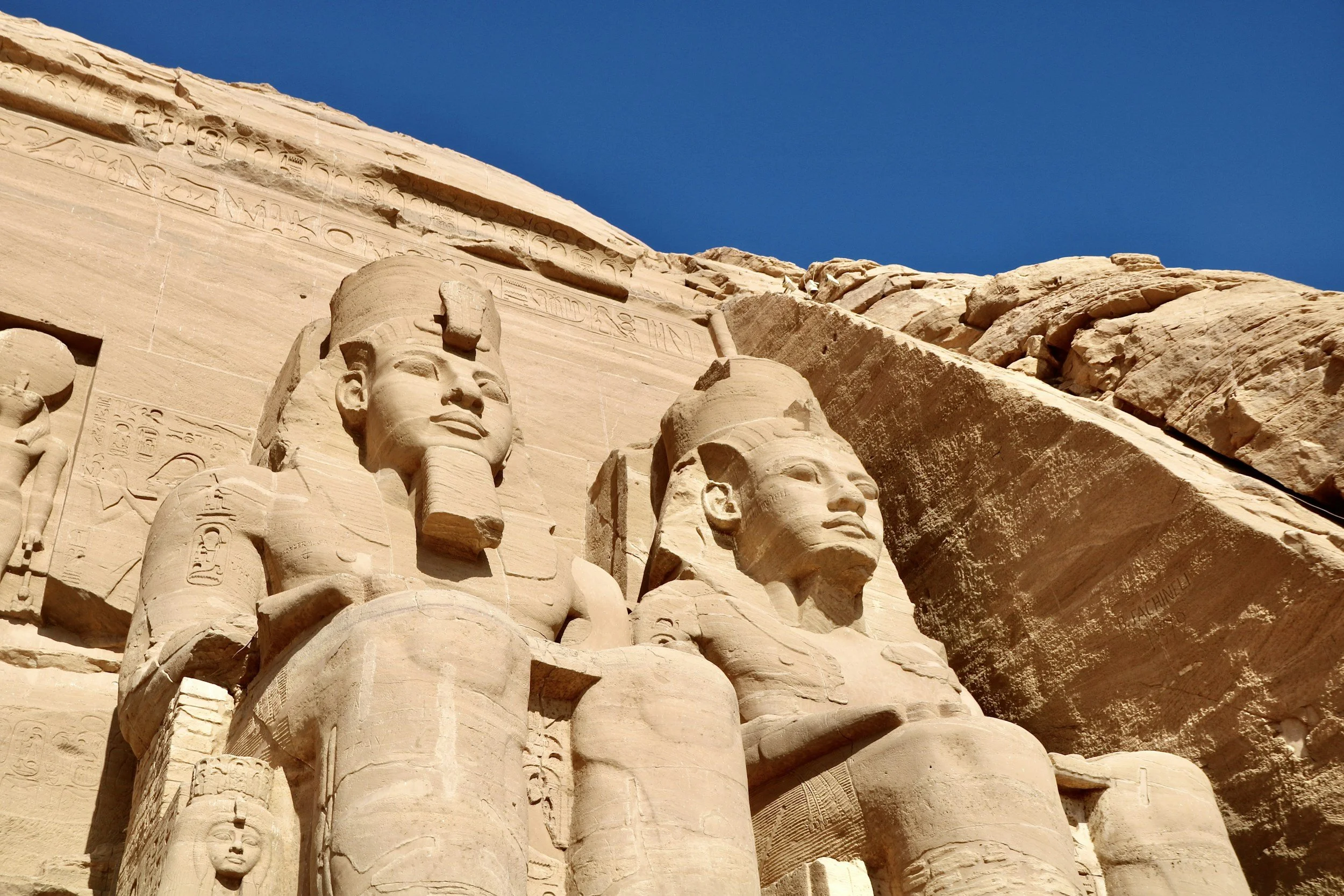 Close-up of the colossal seated statues of Ramesses II carved into the rock facade of Abu Simbel temple, southern Egypt