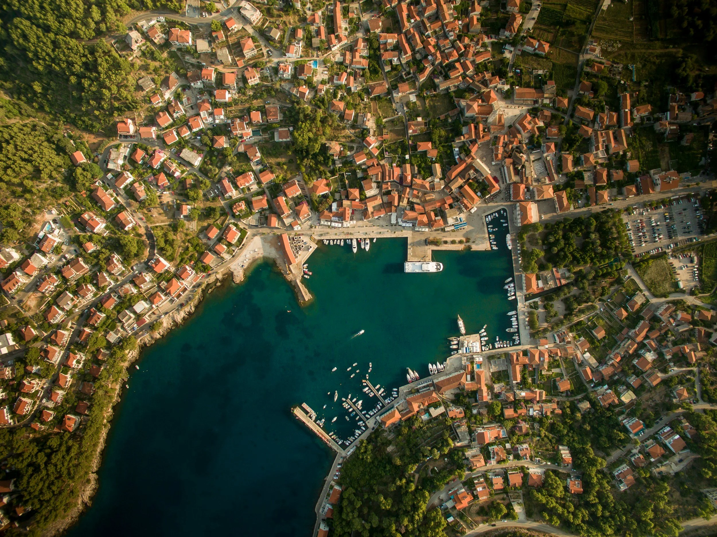 Aerial view of Hvar town with its terracotta-roofed old town, harbour and the deep blue Adriatic Sea surrounded by terraced hills and island coastline, Croatia