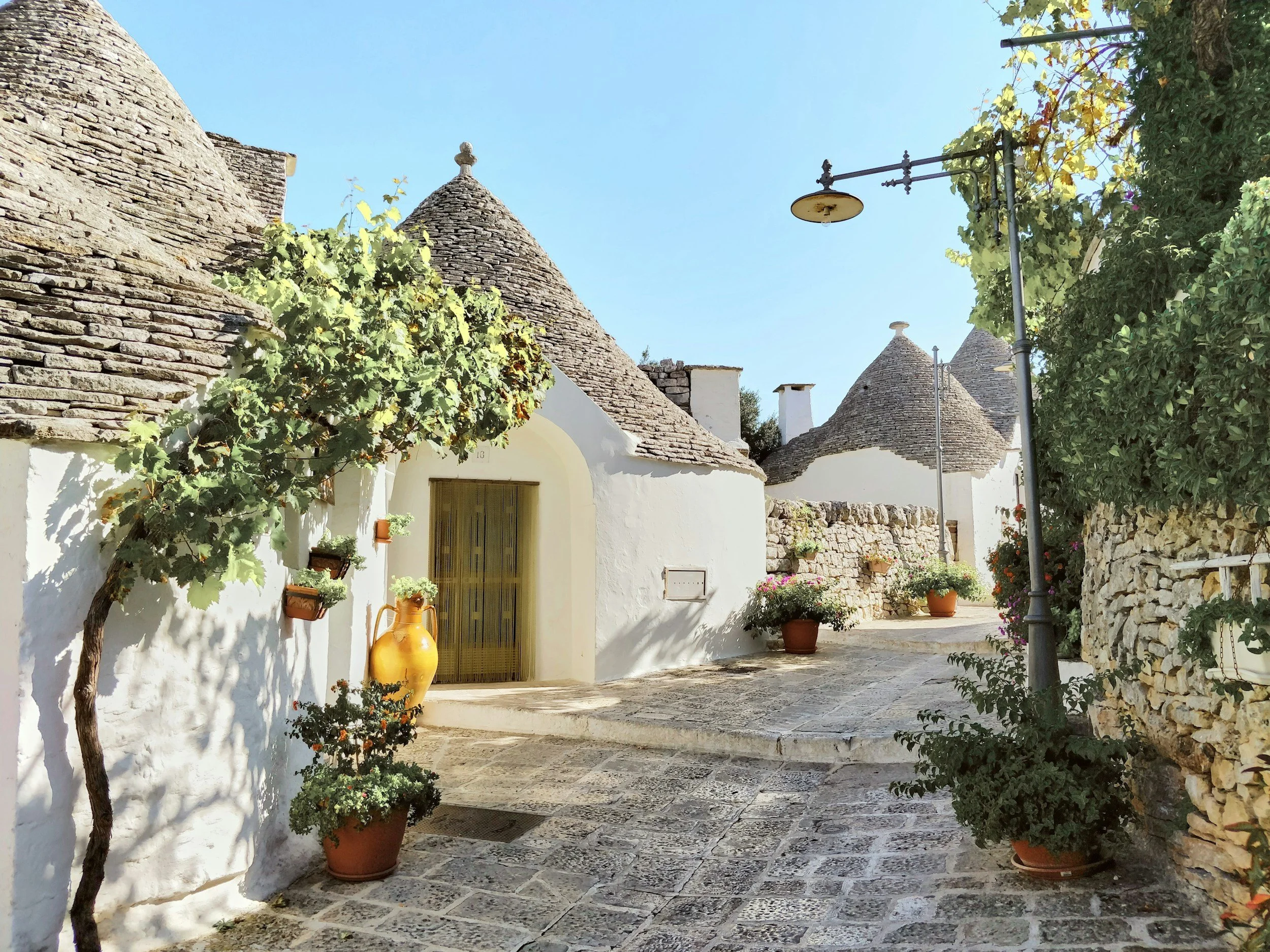 A narrow stone alley lined with whitewashed trulli houses with conical roofs in Alberobello, Puglia, a UNESCO World Heritage Site in southern Italy