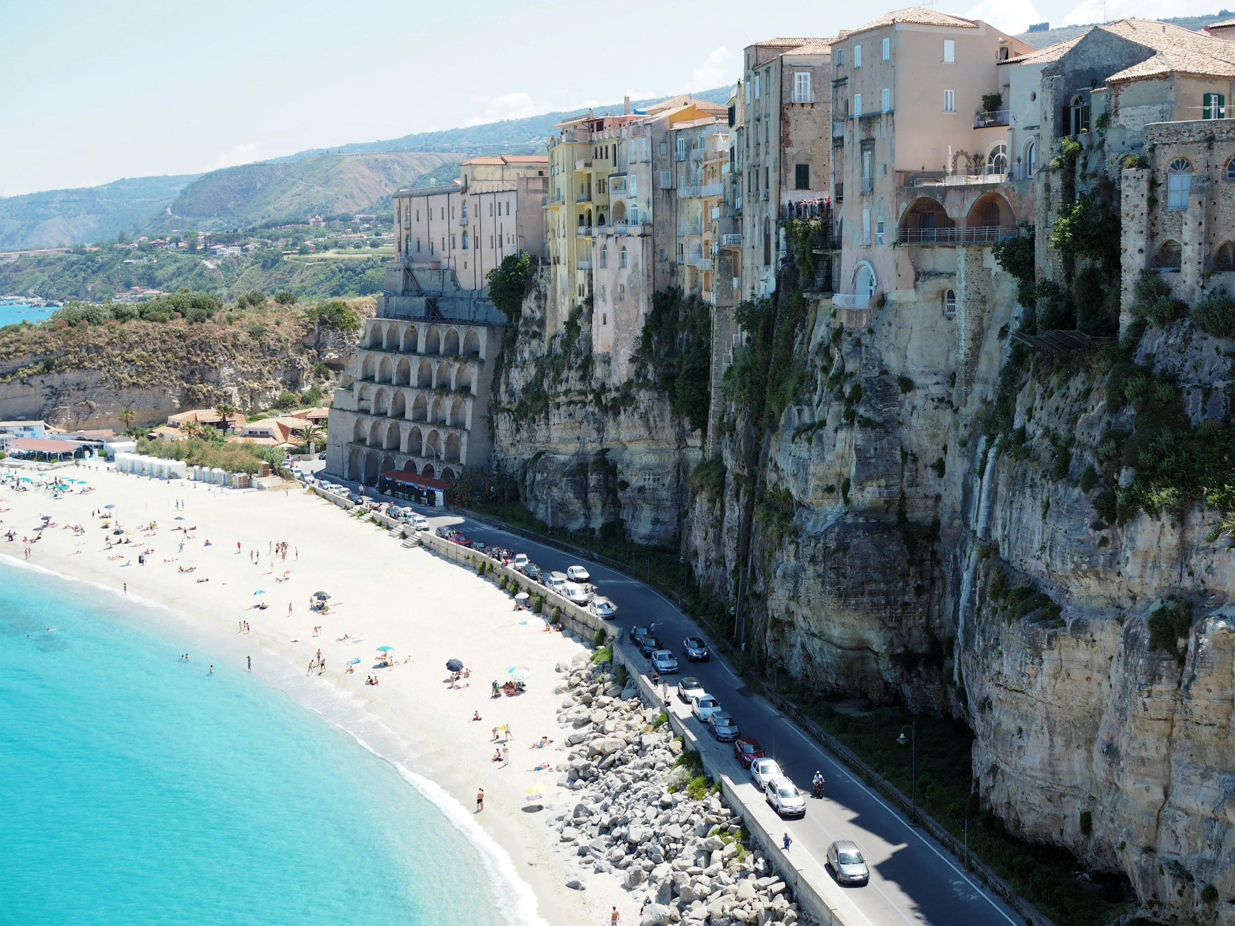 Aerial view of the hilltop town of Tropea perched on sheer cliffs above a turquoise beach in Calabria, one of Italy's most dramatic and least-visited coastlines