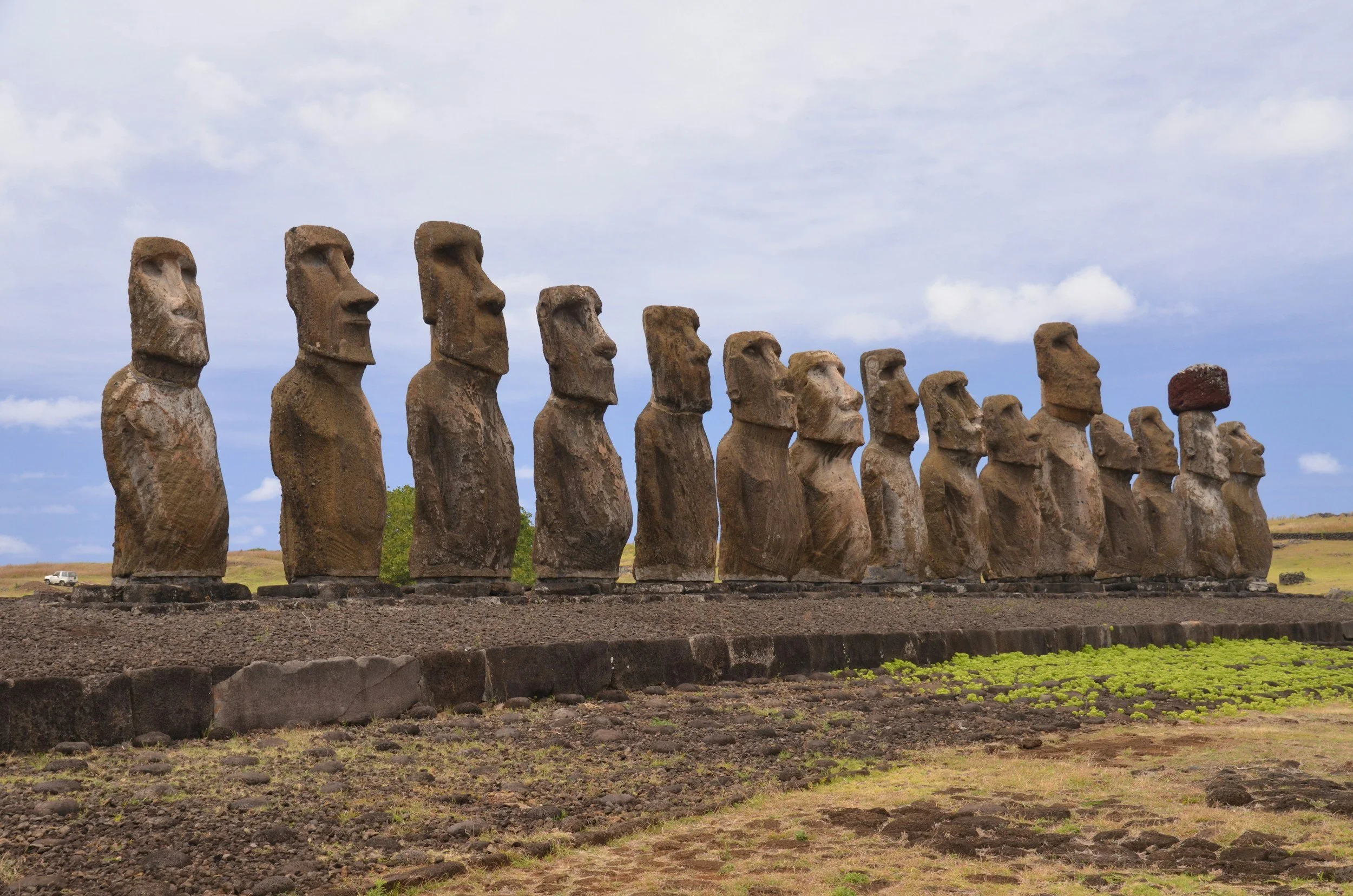 A row of ancient Moai stone statues at Ahu Tongariki on Easter Island, the most remote inhabited island in the world, standing against an overcast sky, Chile