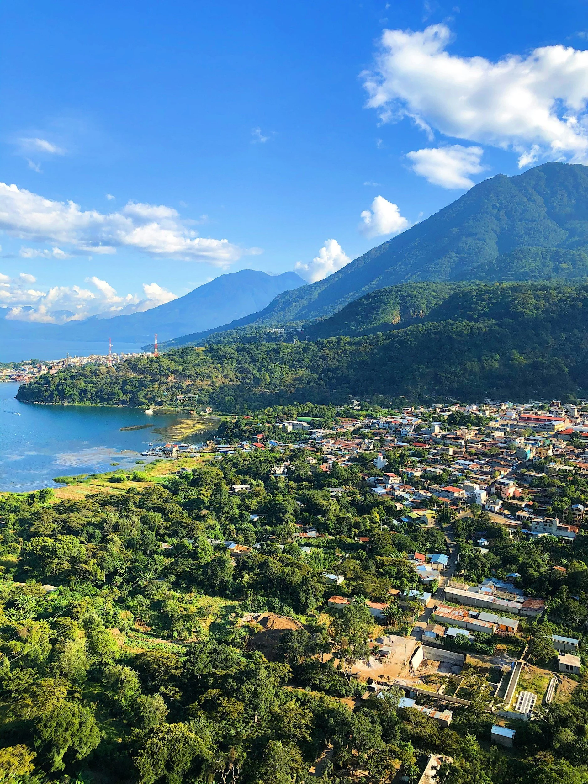Aerial view of Lake Atitlán in Guatemala with a lush volcano rising above the water and a lakeside village nestled along the shore