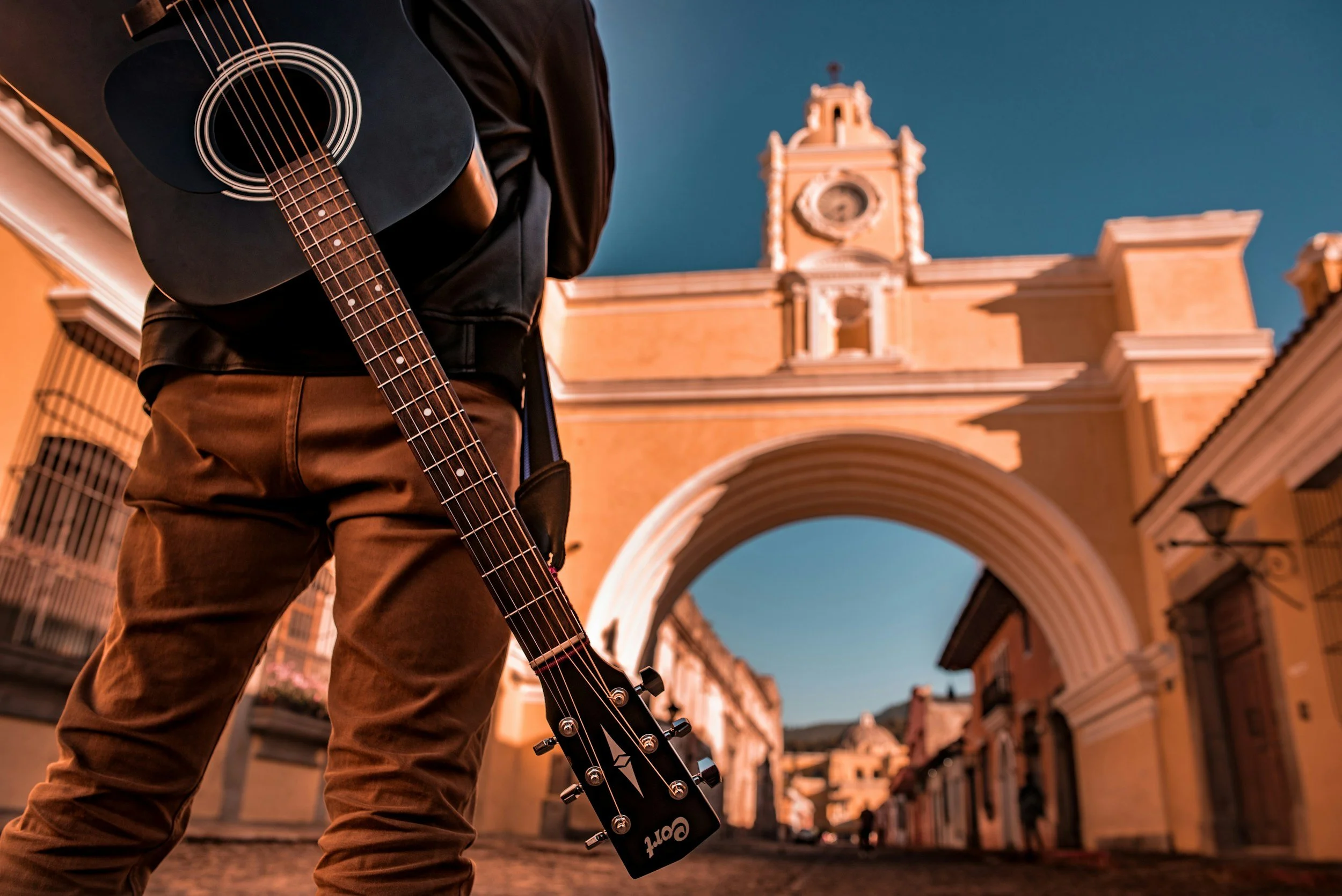 Musician holding a guitar in front of the Santa Catalina Arch in Antigua Guatemala during a traditional Mayan music demonstration on a private cultural tour