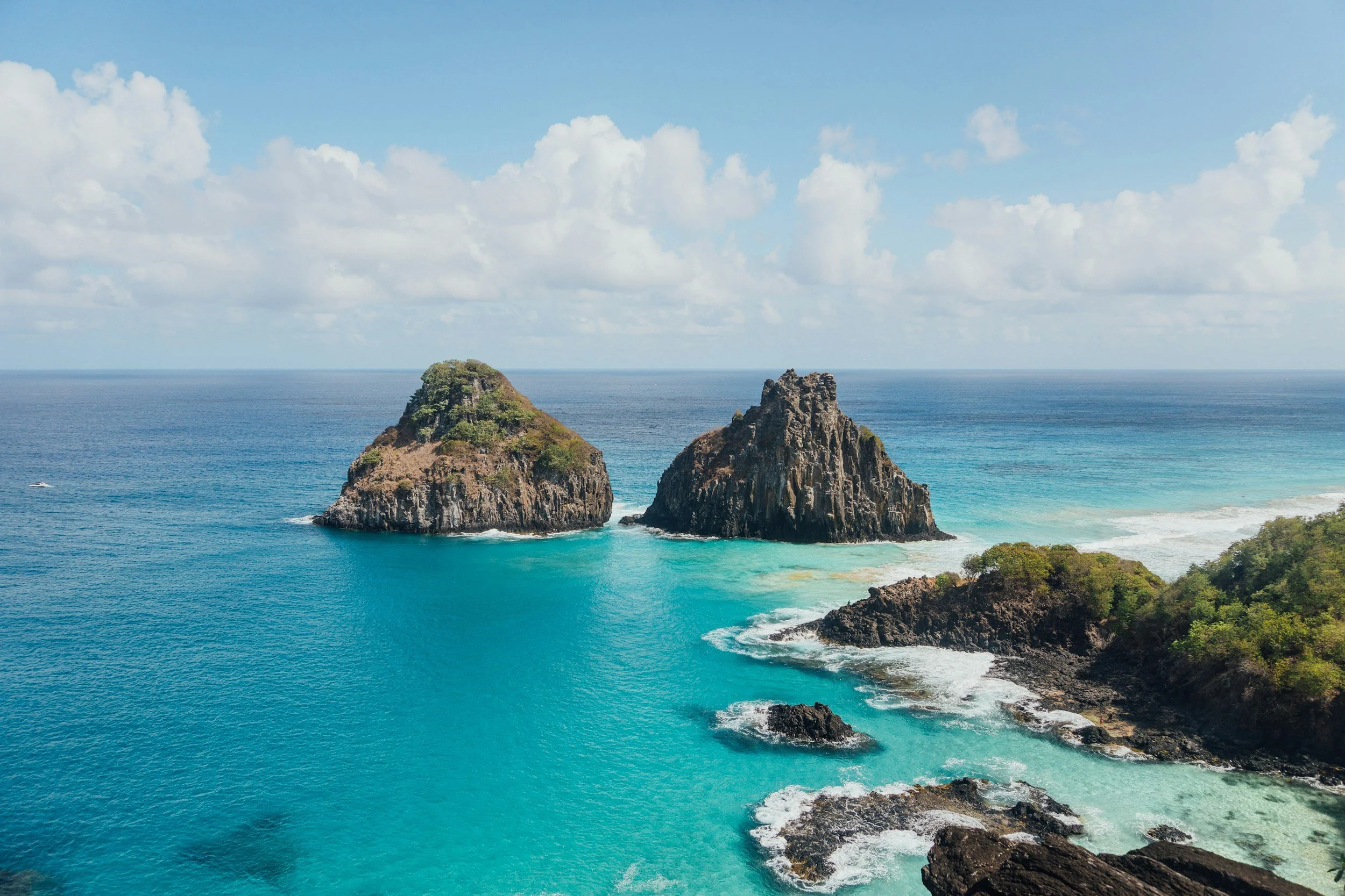 Iconic twin volcanic rock peaks rising from crystal clear turquoise waters off Fernando de Noronha island, Brazil