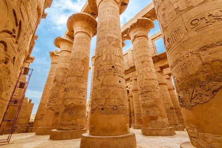 Looking up at the massive carved and painted sandstone columns of the Great Hypostyle Hall at Karnak Temple Complex in Luxor, Egypt