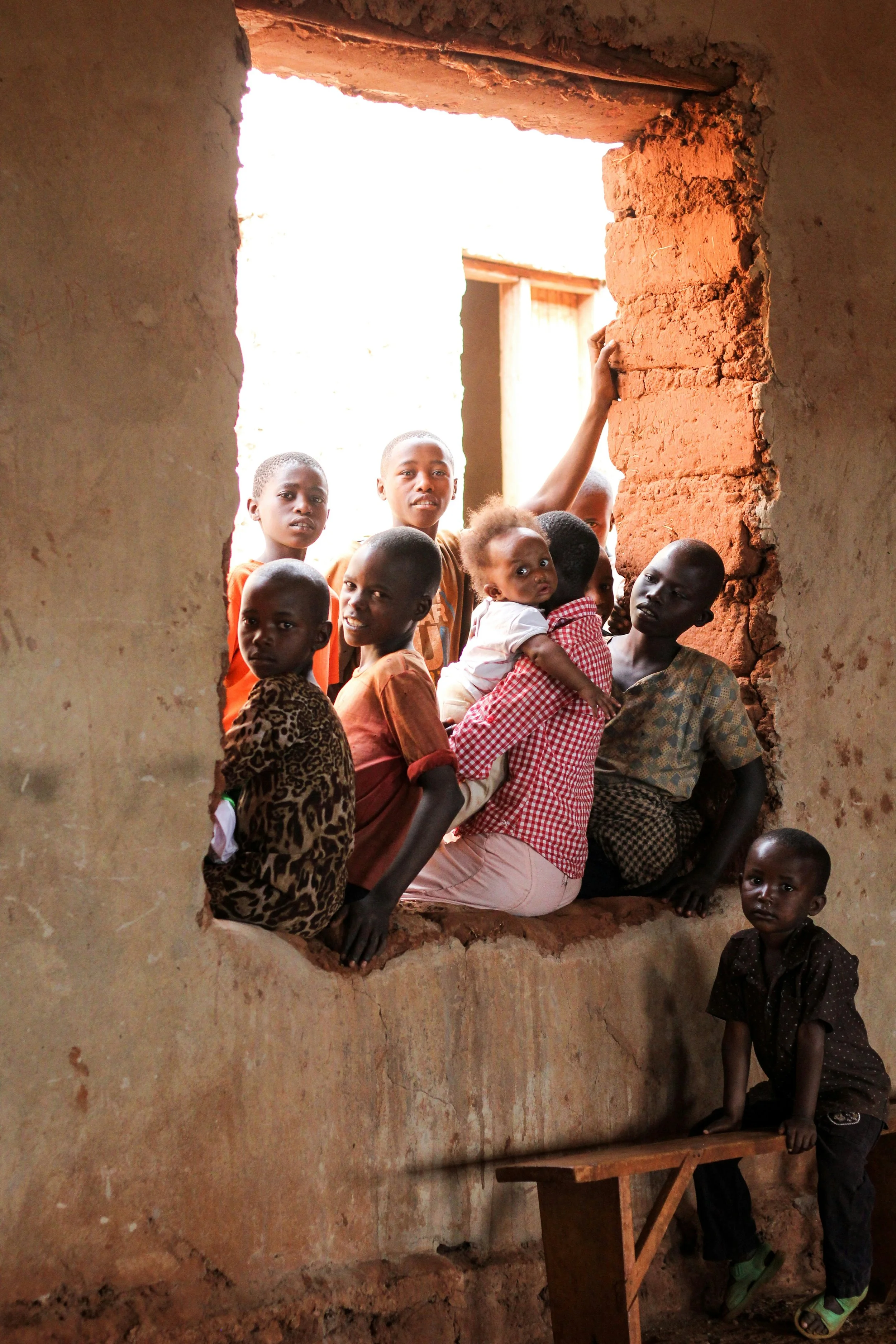 Group of Rwandan children leaning out of a window and smiling in a neighbourhood in Kigali, Rwanda