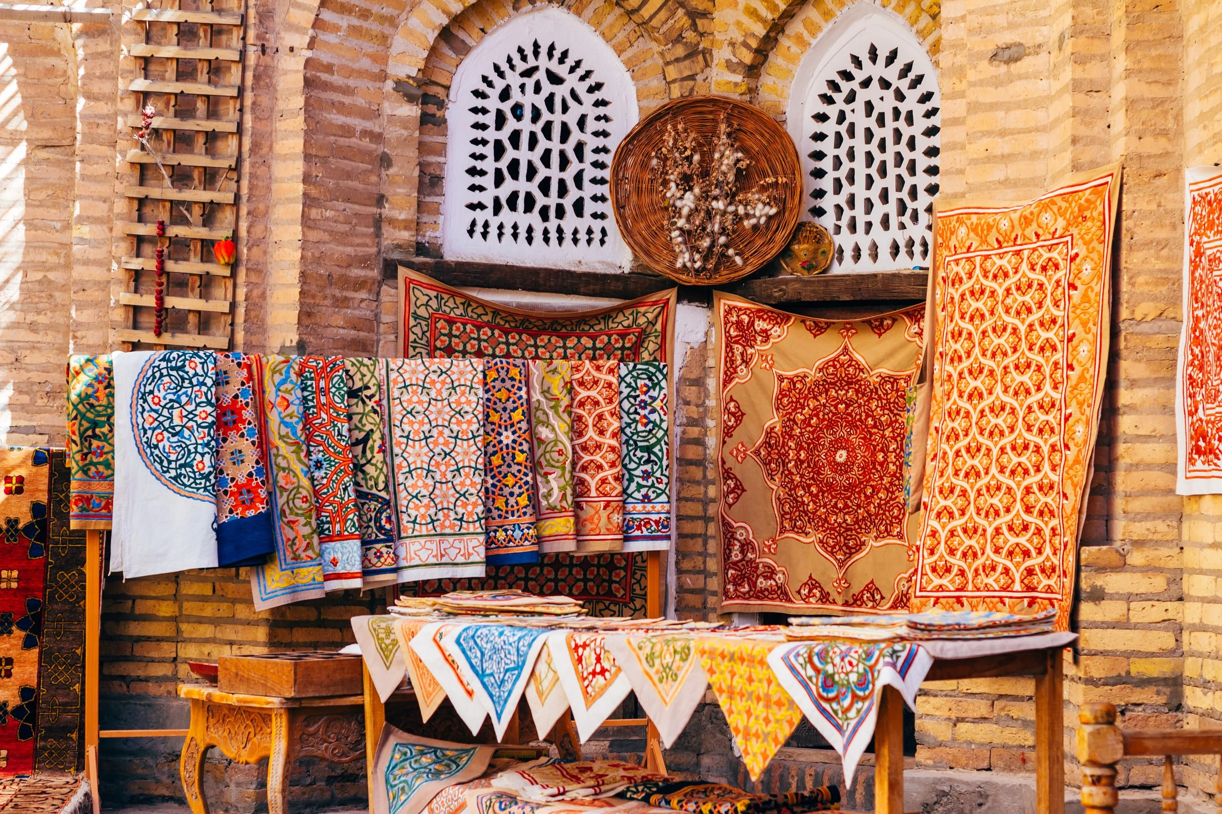 Colourful hand-embroidered suzani textiles and ikat fabrics displayed at a traditional bazaar in Uzbekistan on a private Silk Road journey