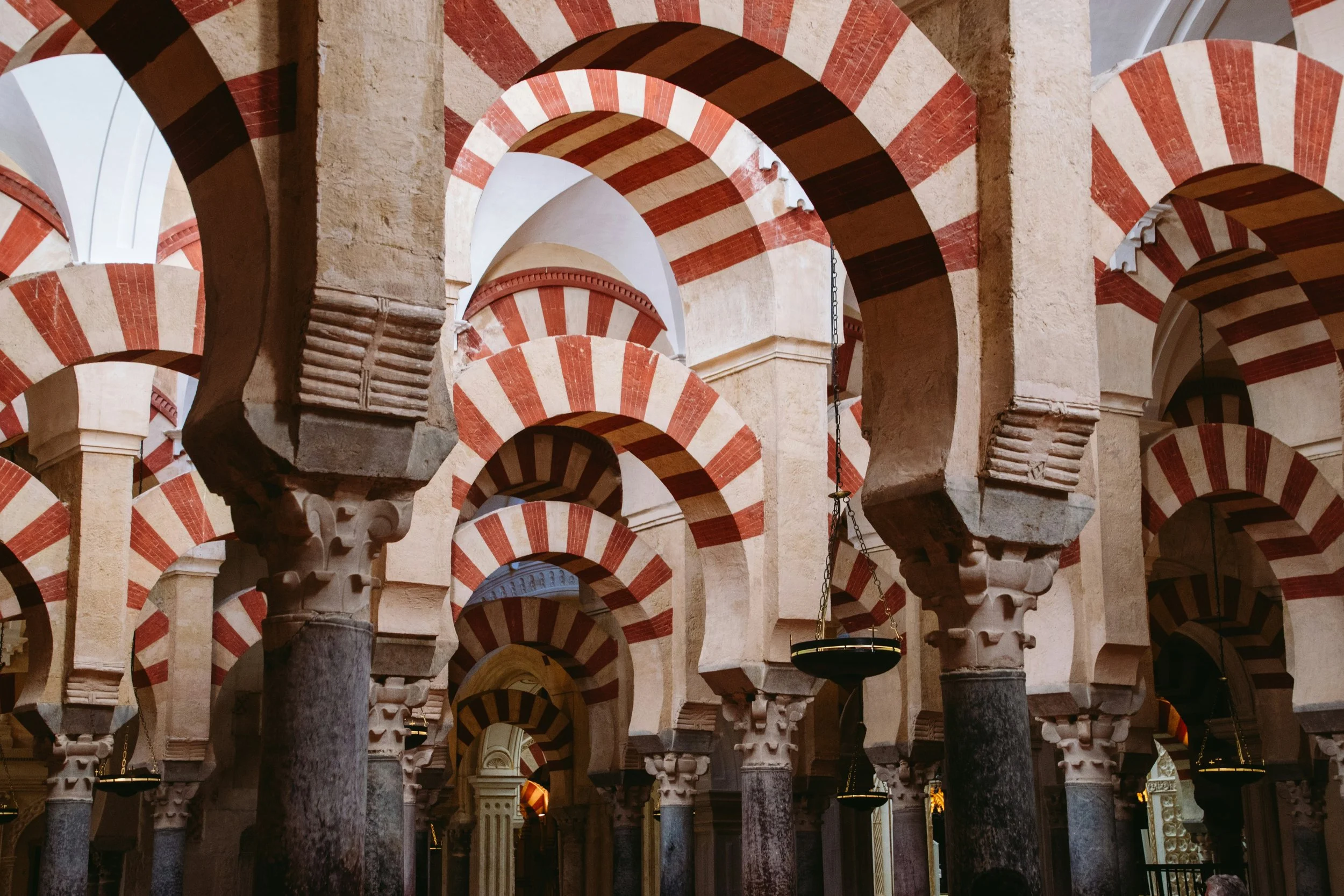 The iconic red and white striped double arches of the Mezquita-Catedral of Córdoba receding into the distance in the hypostyle prayer hall, Andalucía, Spain