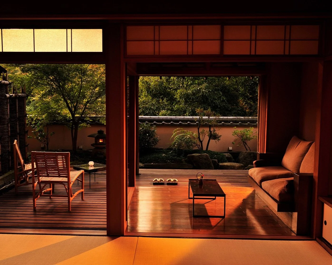 Elegant ryokan interior with tatami floors and sliding doors opening onto a traditional Japanese garden at sunset