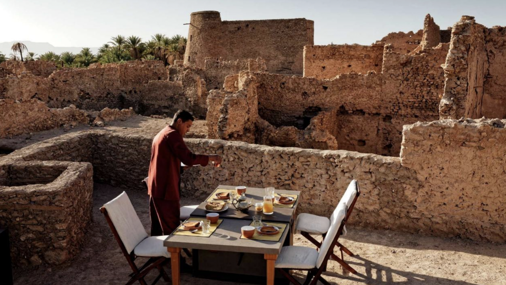 Private outdoor dining table set among ancient kasbah ruins on The Memory Road, Morocco