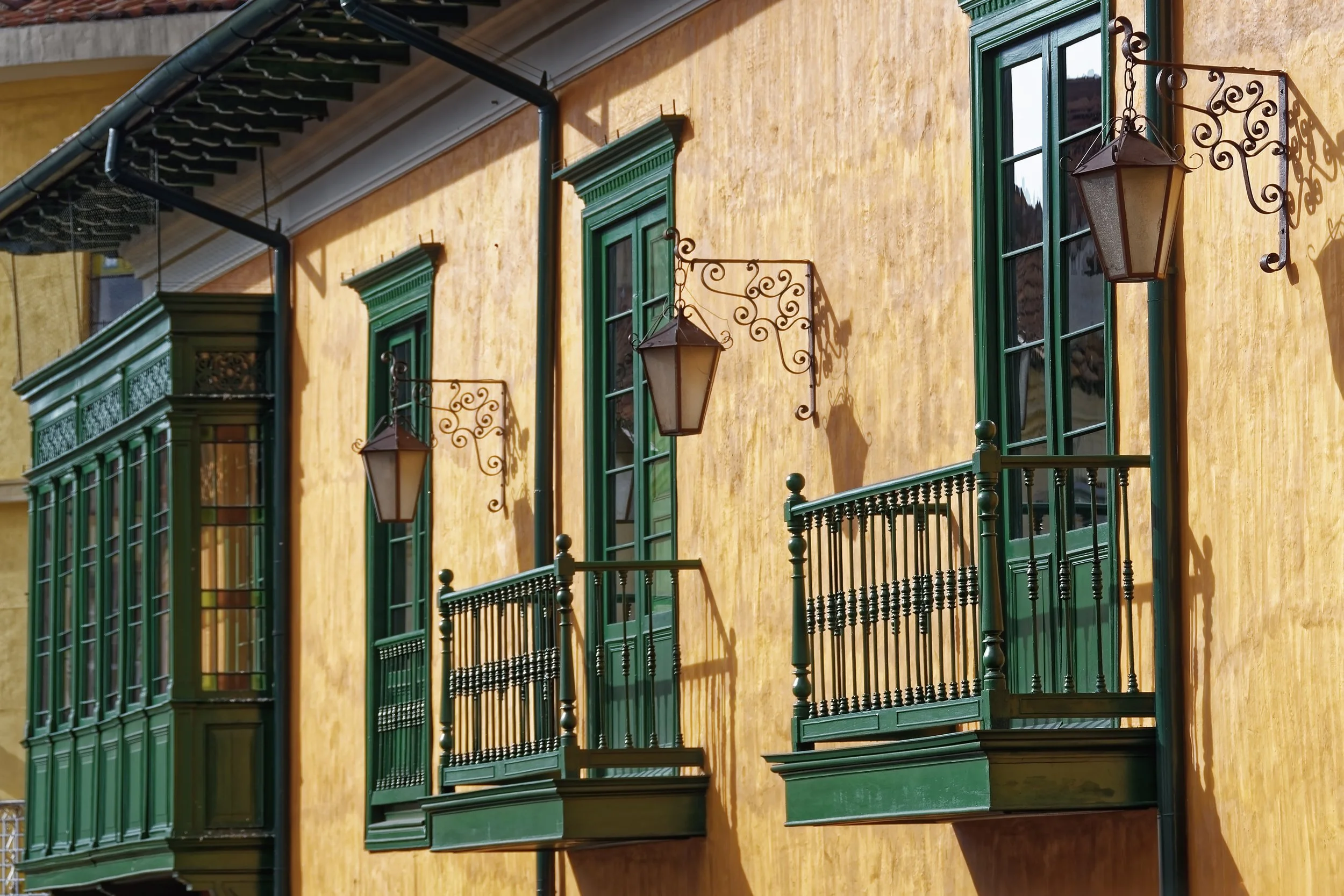 Ornate green wrought-iron balconies and lanterns on a colonial building near the Gold Museum in Bogotá, Colombia