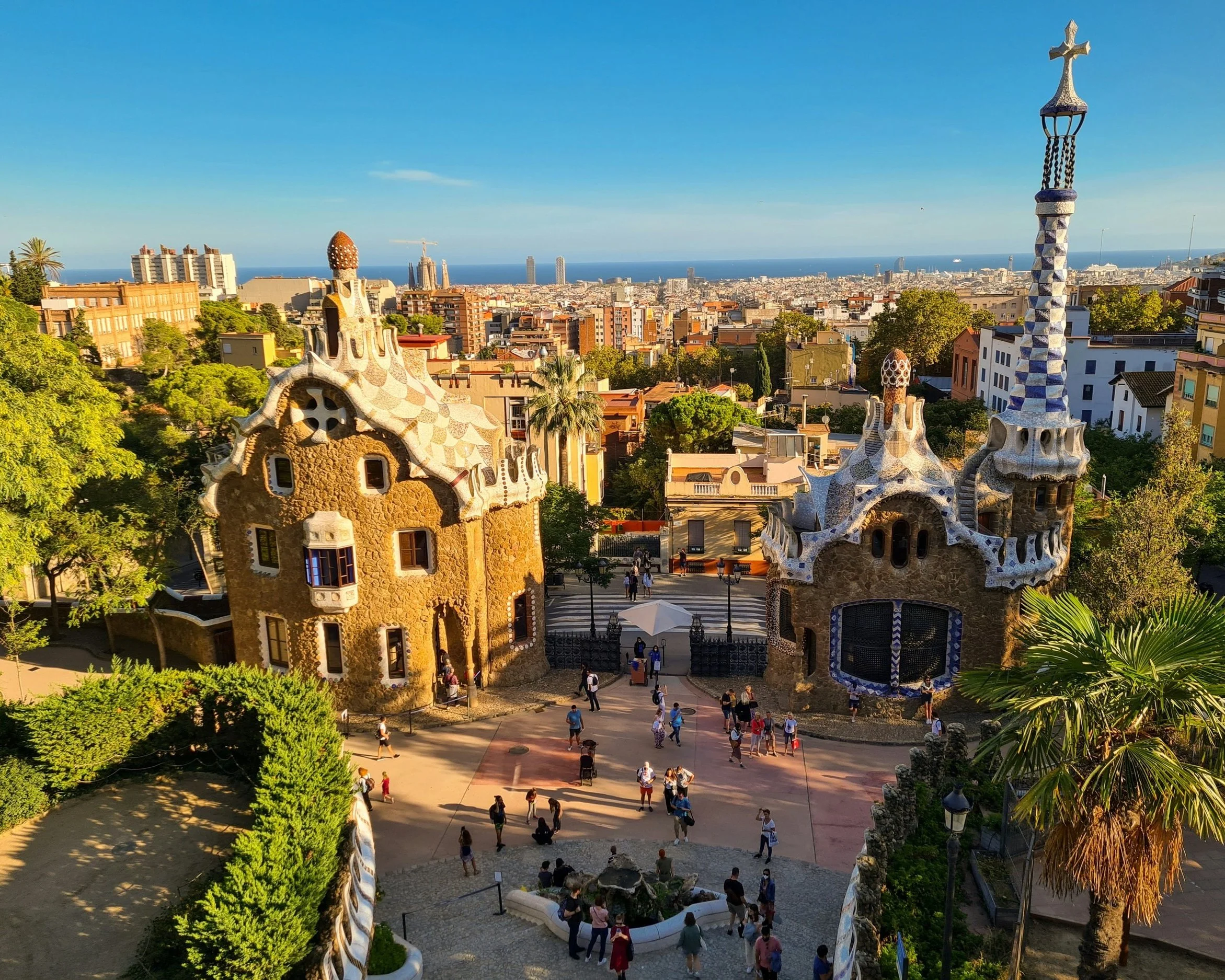 Aerial view of the mosaic gatehouse pavilions of Park Güell designed by Antoni Gaudí, overlooking the rooftops of Barcelona and the Mediterranean beyond, Spain