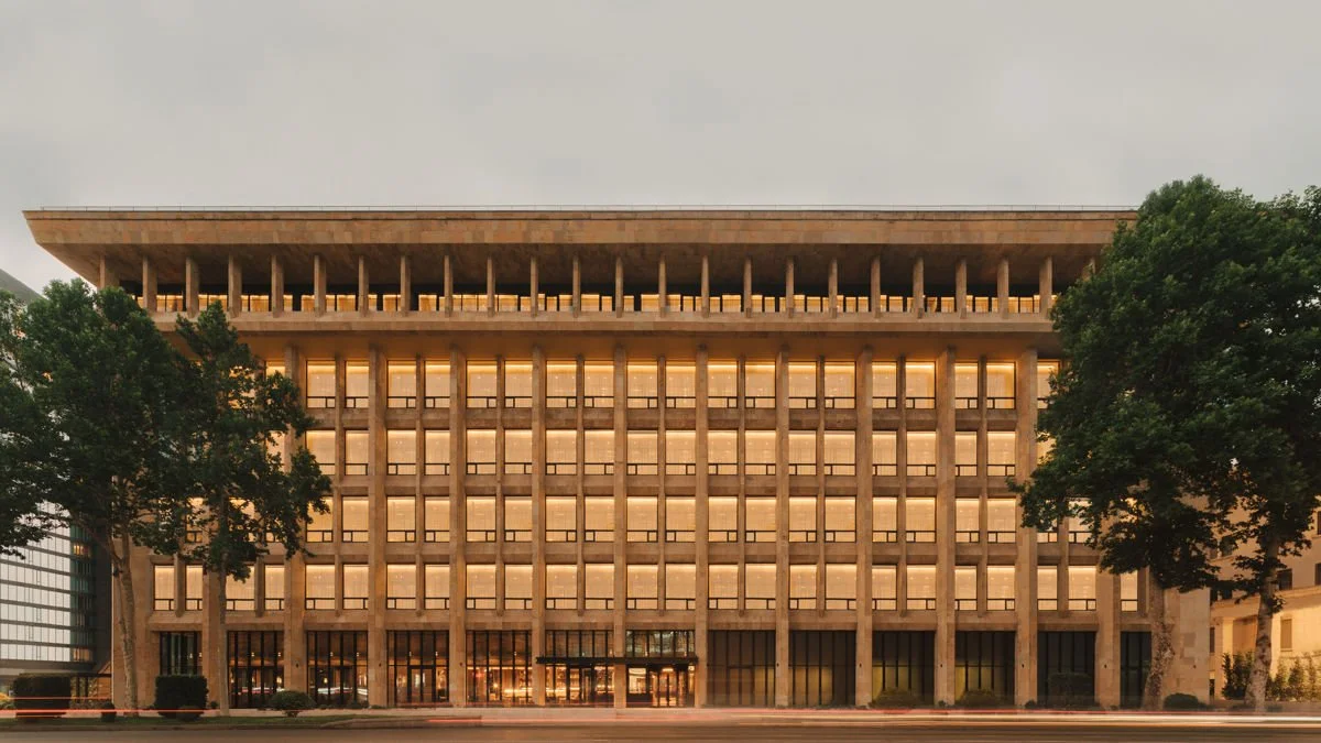 Imposing Soviet-era brutalist building with rows of uniform windows illuminated at dusk in Tbilisi, Georgia, offering a unique heritage accommodation experience