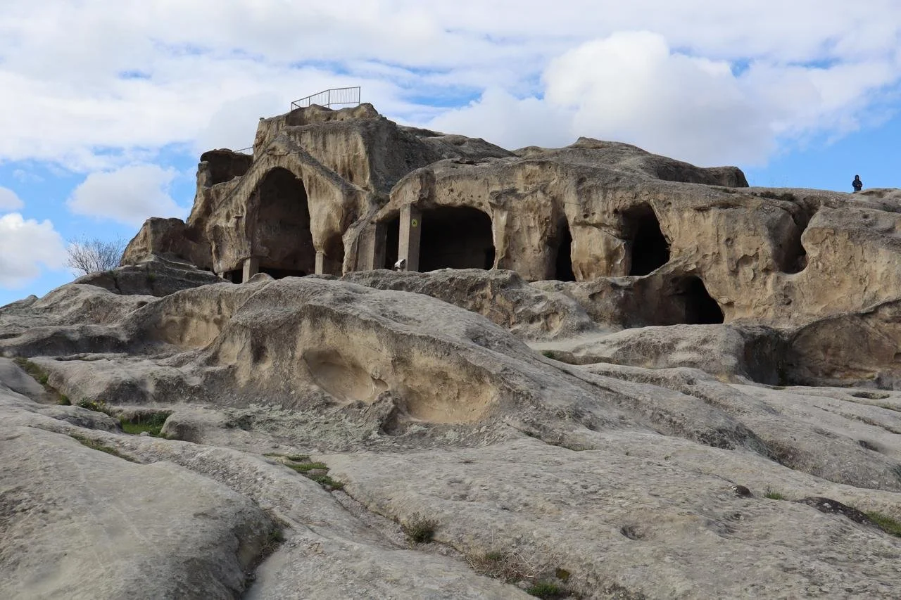 Ancient rock-hewn cave dwellings and arched chambers carved into sandstone cliffs at Uplistsikhe cave city in the Shida Kartli plains of Georgia