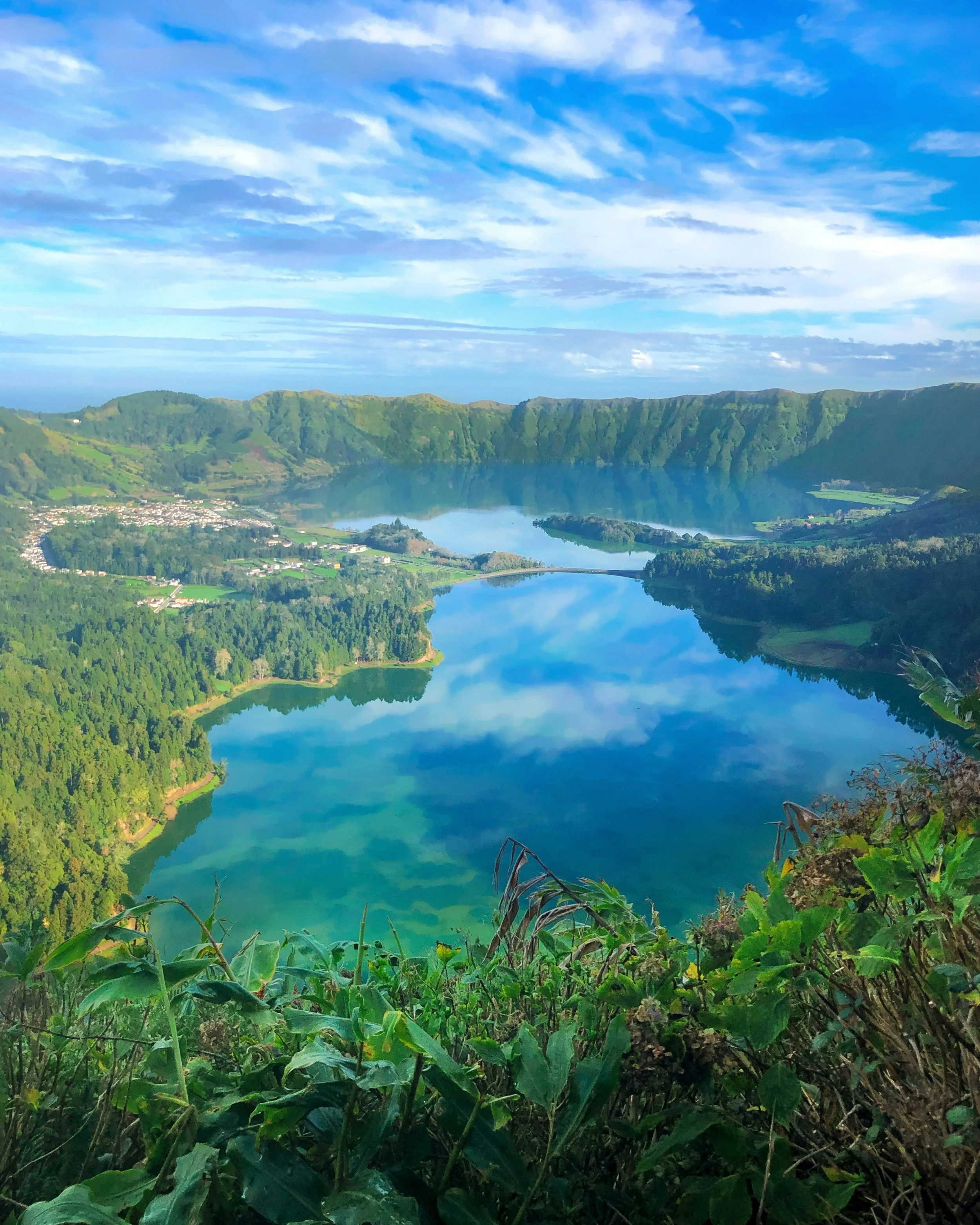 The twin volcanic crater lakes of Sete Cidades on São Miguel island in the Azores, surrounded by lush green calderas and a small village on the lakeside, Portugal