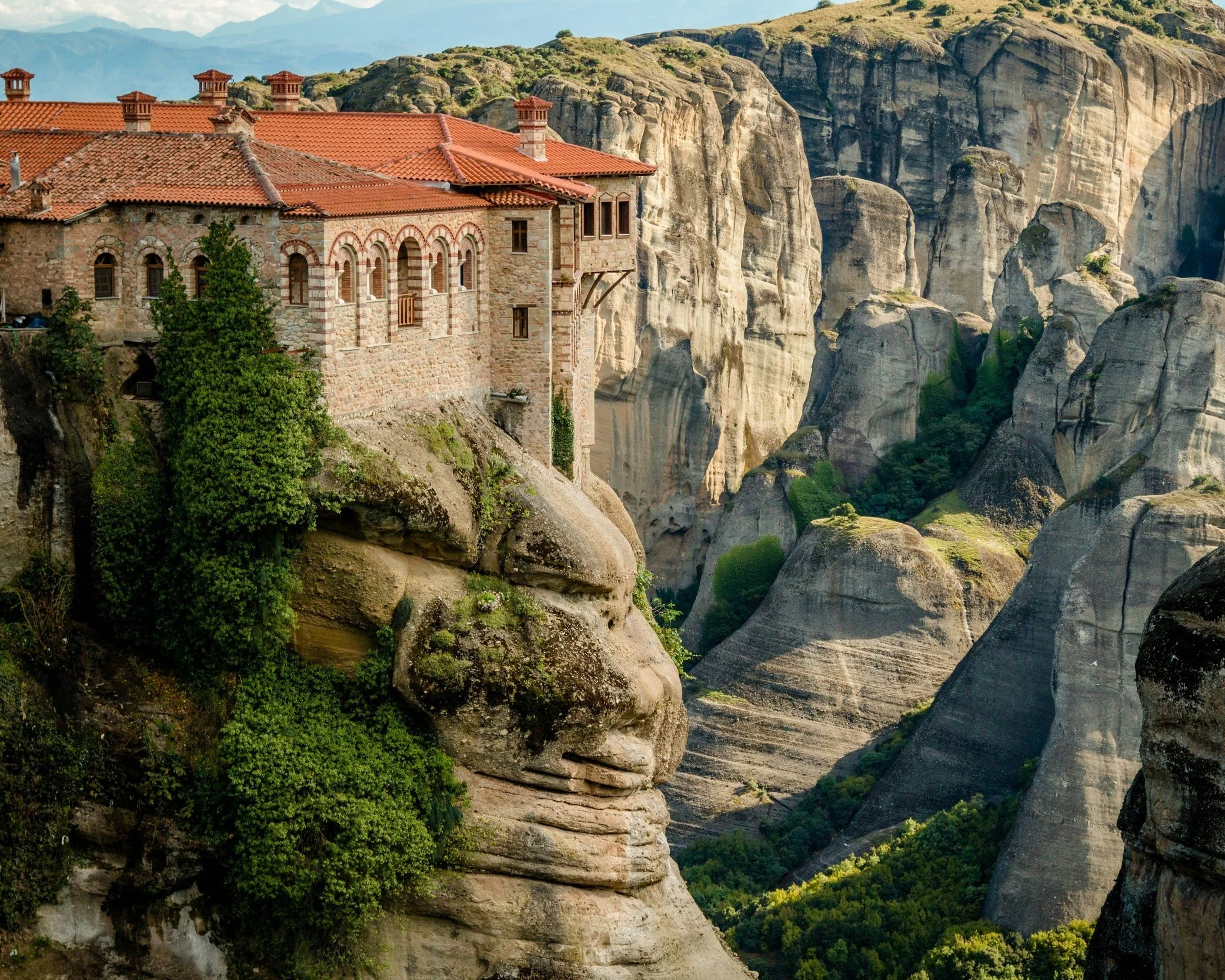 A Byzantine monastery with a red-tiled roof perched dramatically on top of a sheer rock pillar at Meteora, Thessaly, Greece