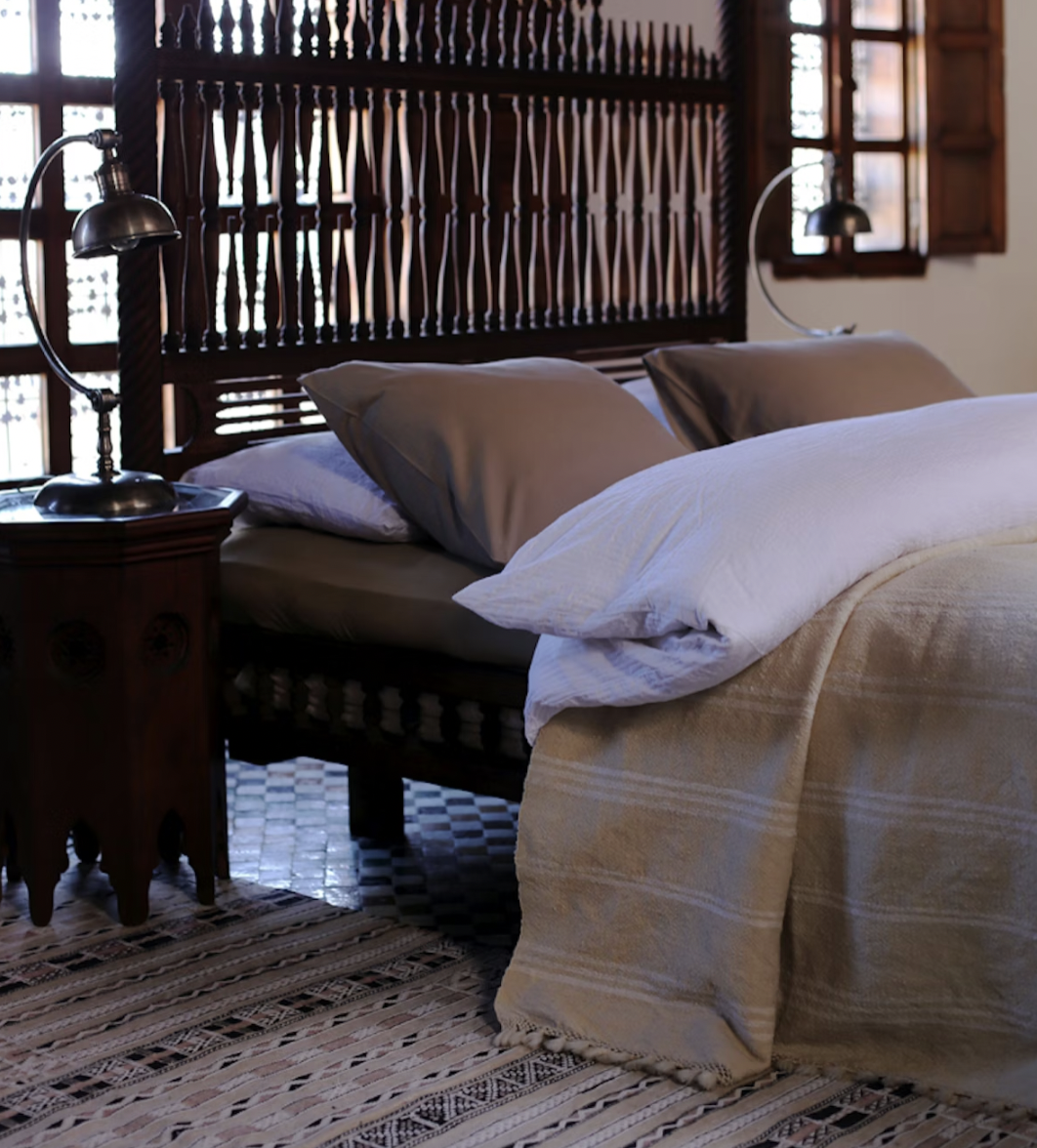 A cozy bedroom with a wooden headboard, white and brown bedding, and two matching bedside lamps with metal shades.