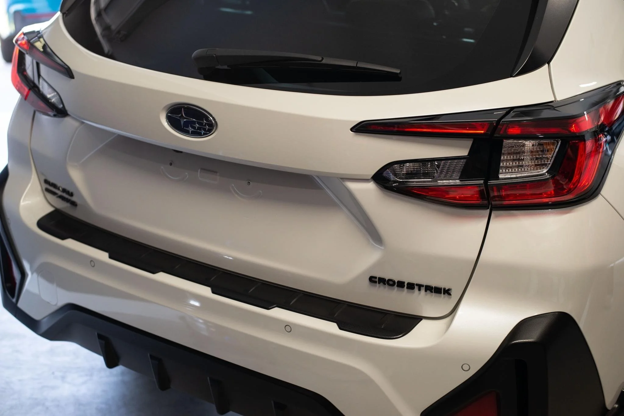 Rear view of a white Subaru Crosstrek displayed in a garage.