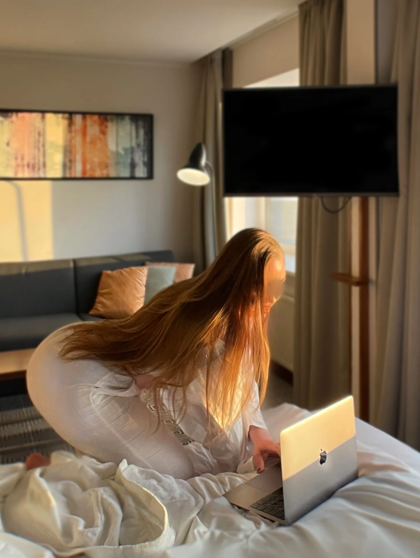 long haired woman bending down to use Apple laptop