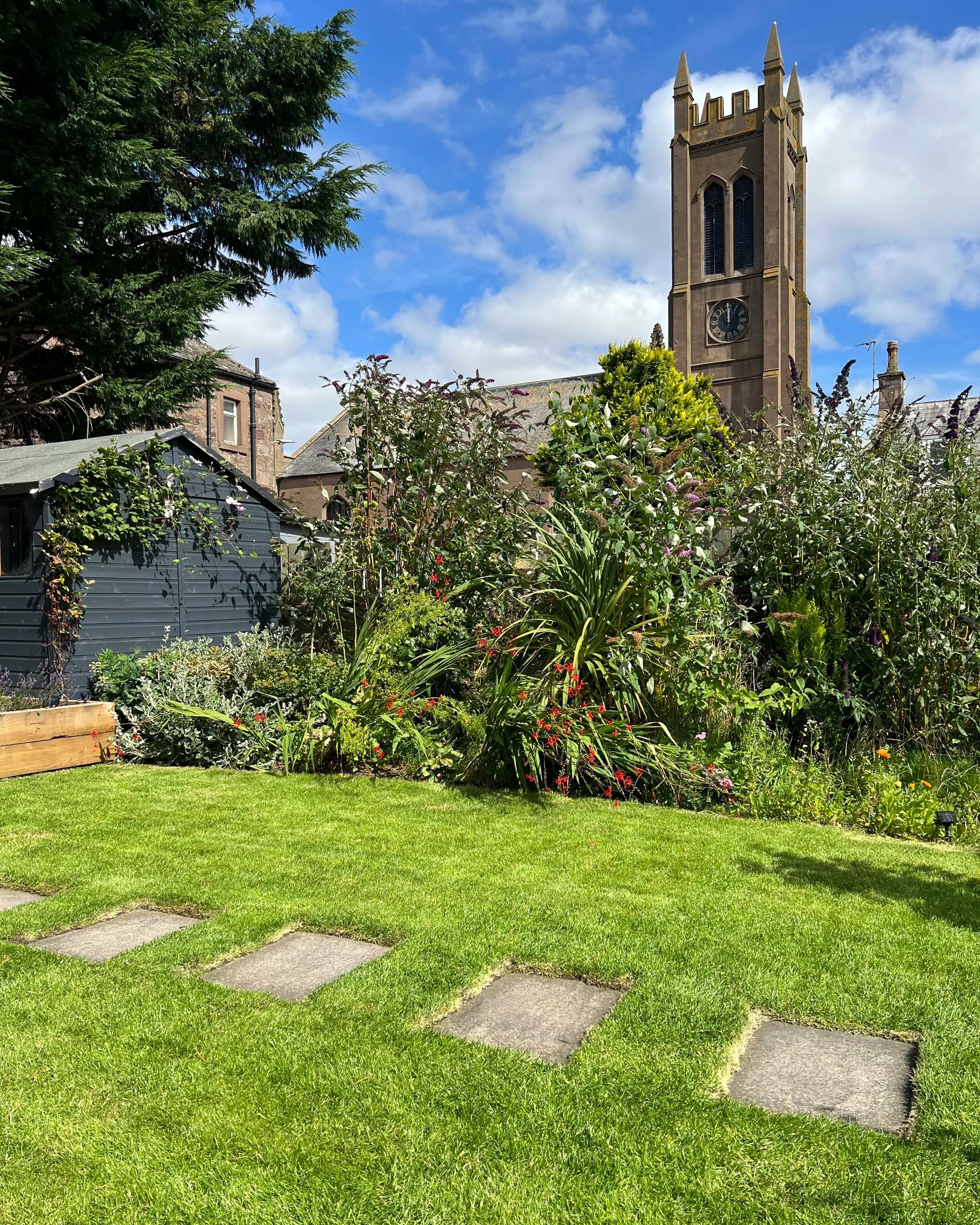 A lush garden with green grass and colourful plants which has been built and maintained by Oak & Sparrow garden maintenance. If you want your garden to look immaculate contact Oak & Sparrow.