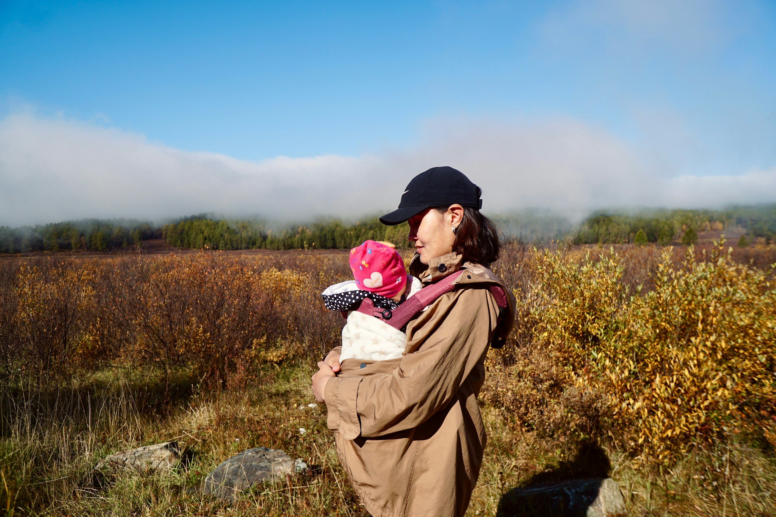 Parent snuggling their child closing in an open field.