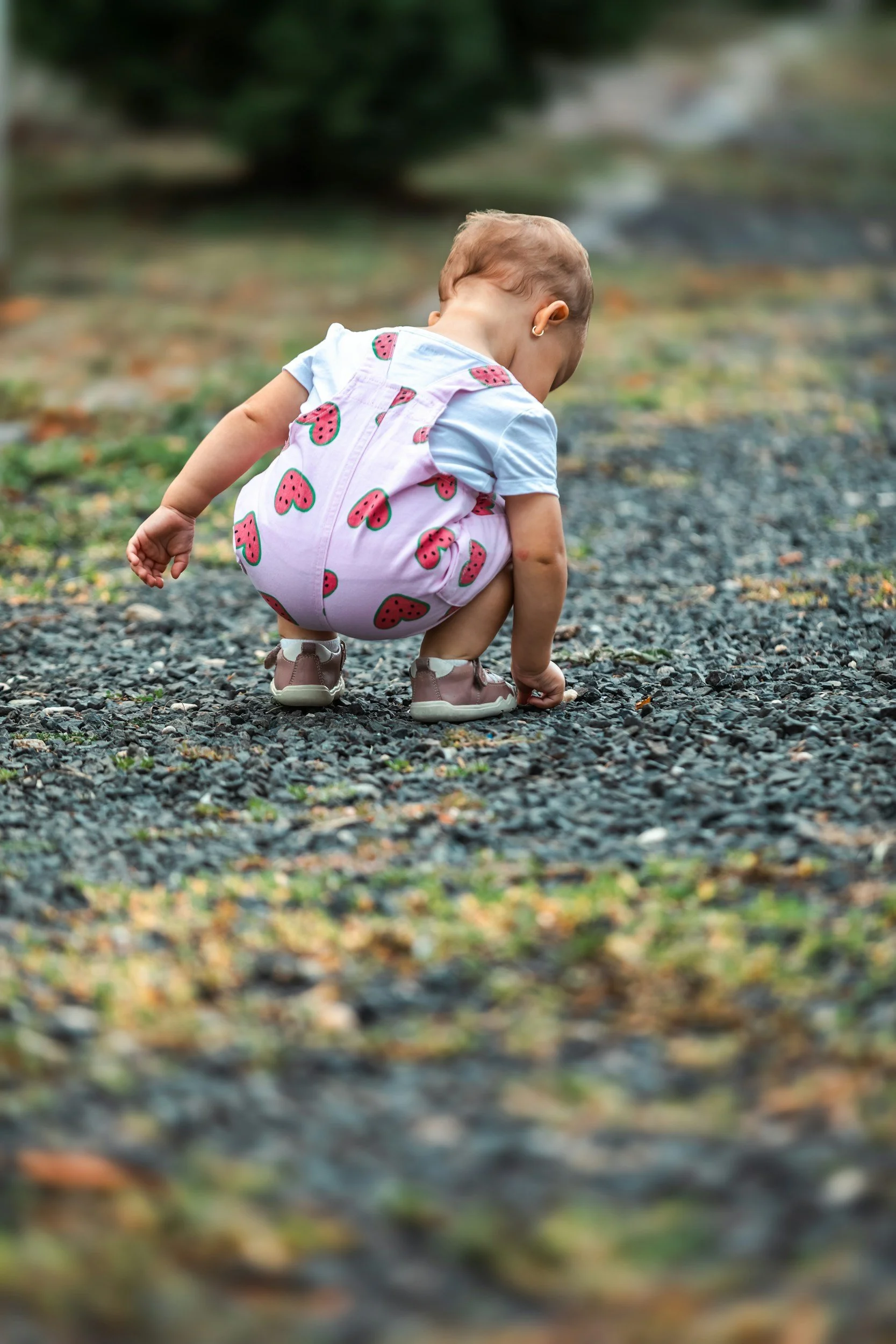 Child exploring the pebbles on the ground.