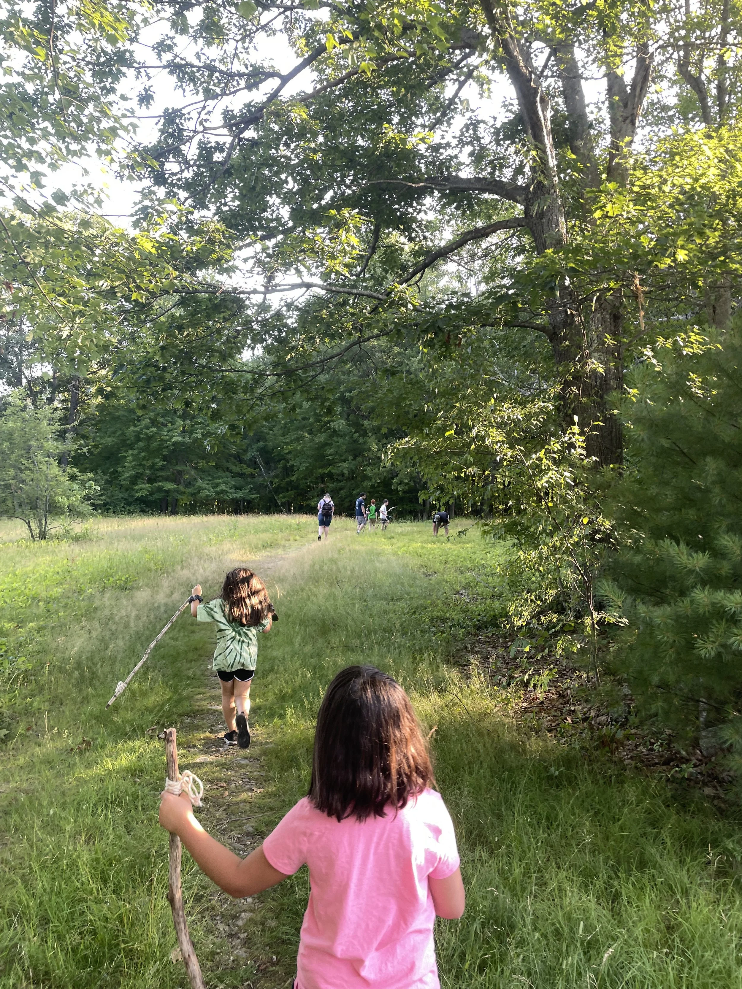 Girls walking down a trail with walkings sticks during Nature Navigators program.