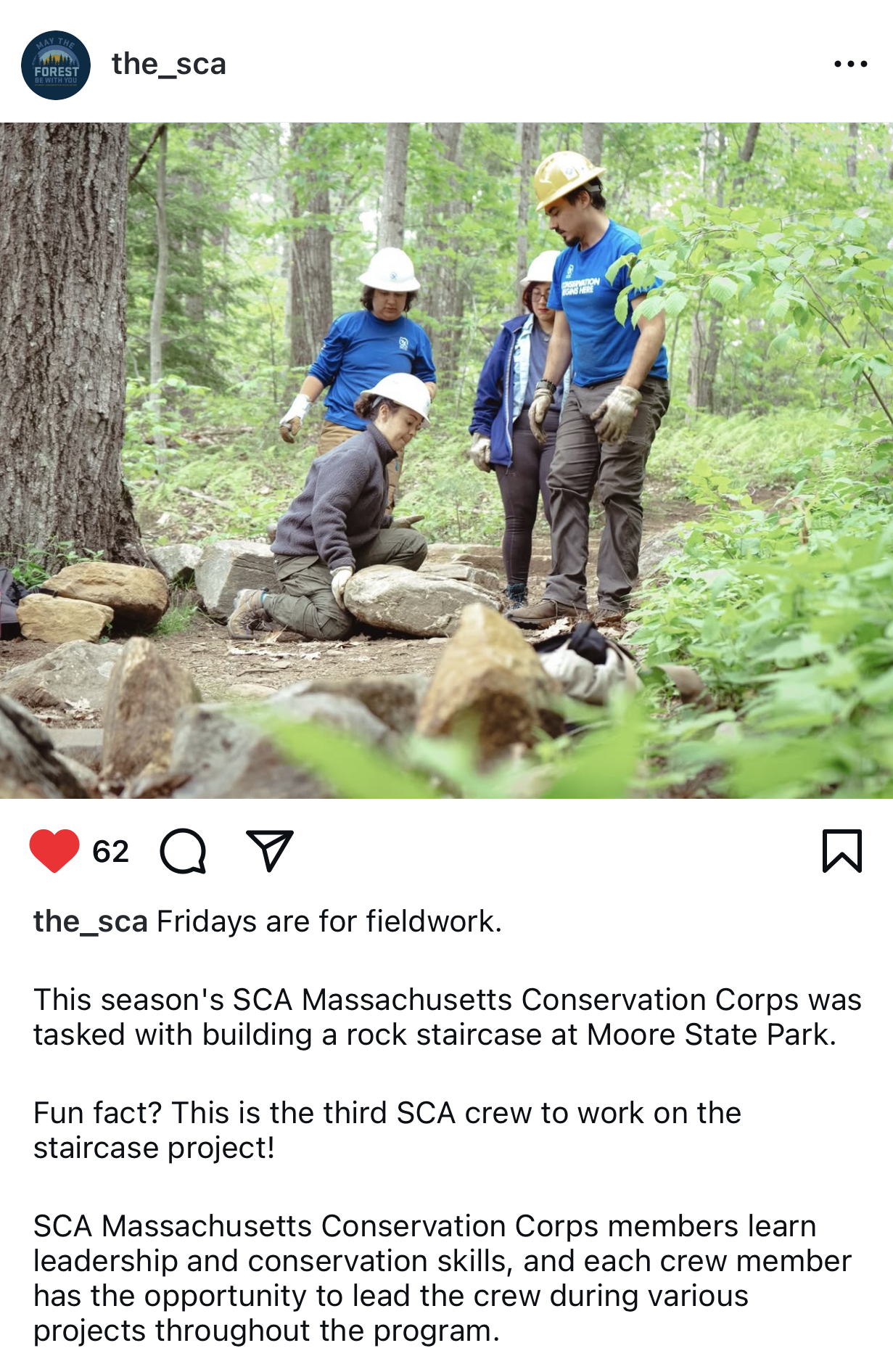 Four young people wearing safety helmets and work gloves building a rock staircase in a forest at Moore State Park.