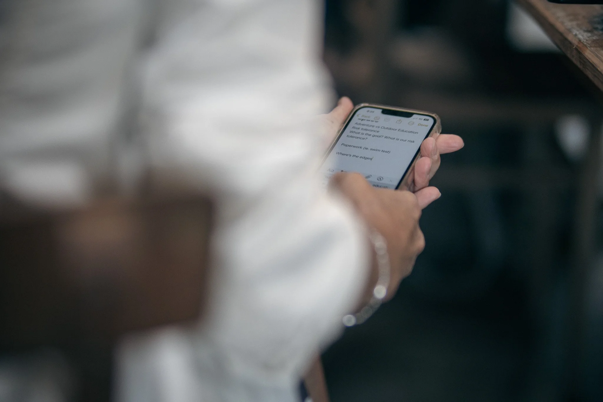 Close-up of a person holding a smartphone with notes or a checklist displayed on the screen, partially visible, with a focus on the hand and phone.