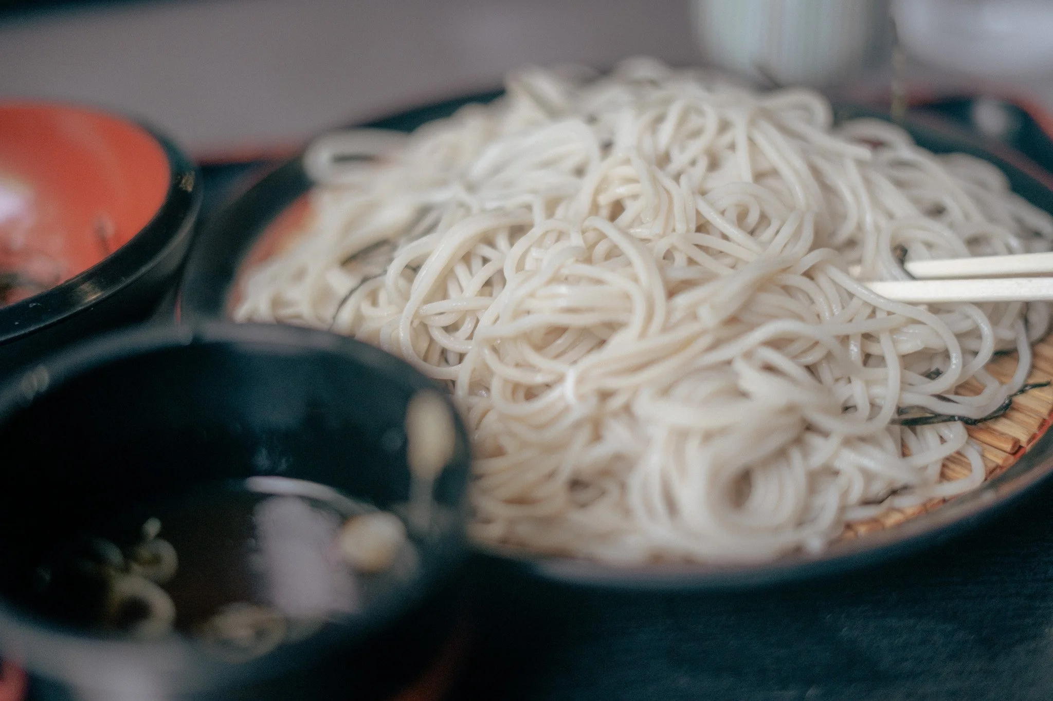 A plate of cooked white noodles with chopsticks on the side.