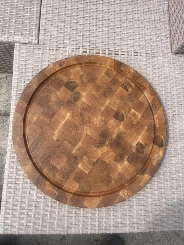 A round wooden serving tray with a checkered pattern, on a textured white surface.