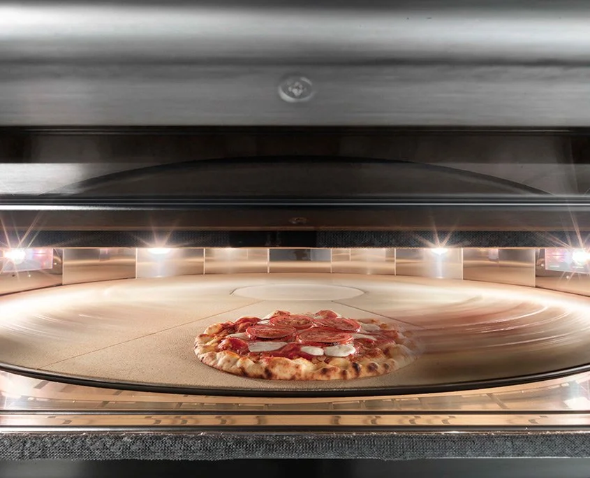 Rotating deck of the Giotto oven with a pizza baking evenly for consistent results.