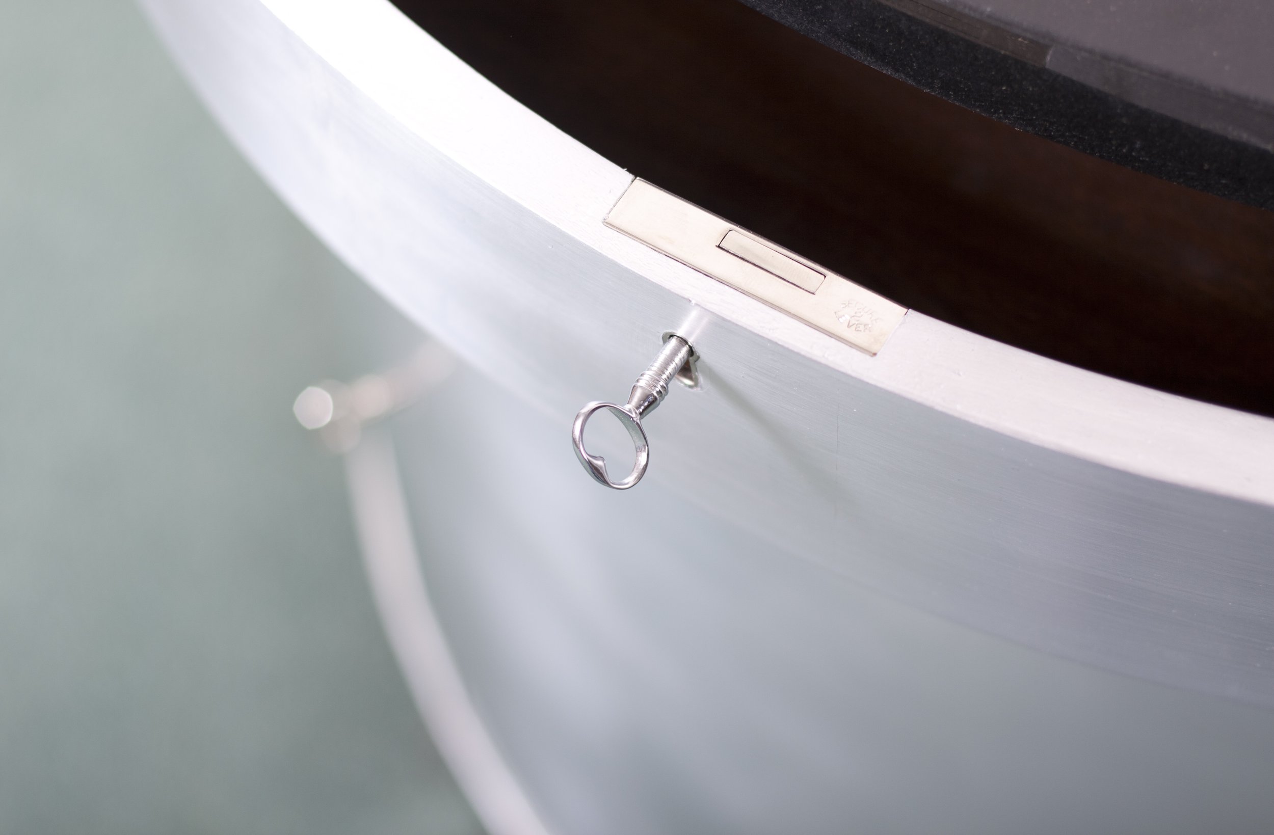 Close up detail showing solid nickel bespoke lock and key in a silver hand painted curved furniture cabinet.
