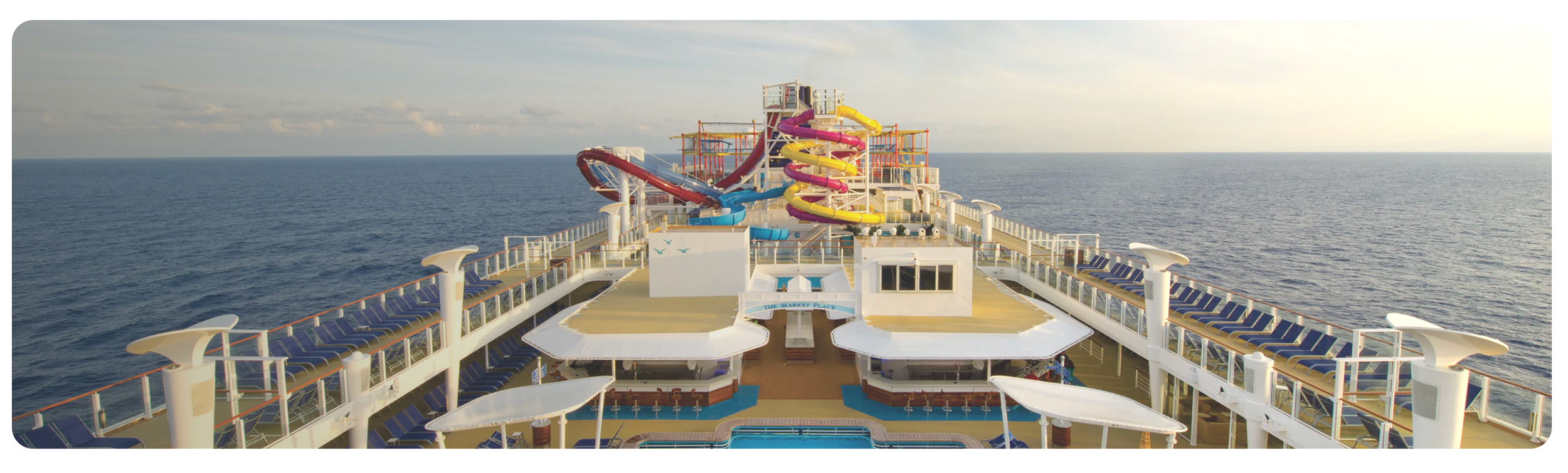 Pool deck on the NCL Breakaway ship showing water slides, pool and pool bars with the ocean in the background.
