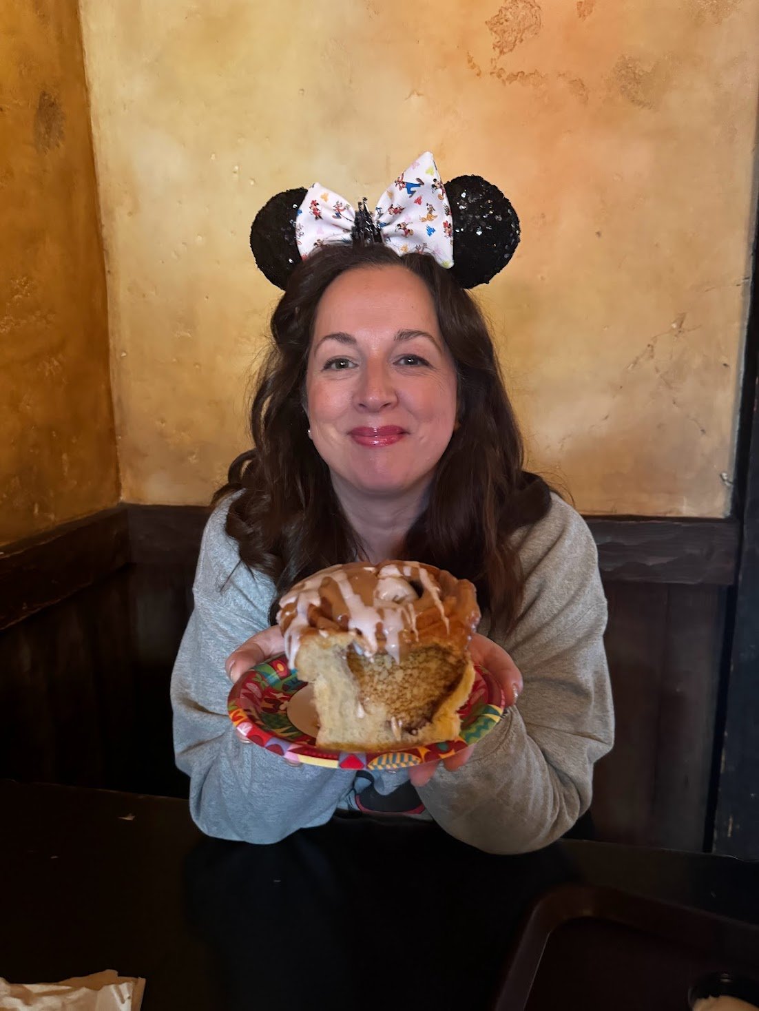 Celeste at Gaston's Tavern in Magic Kingdom holding a giant cinnamon roll